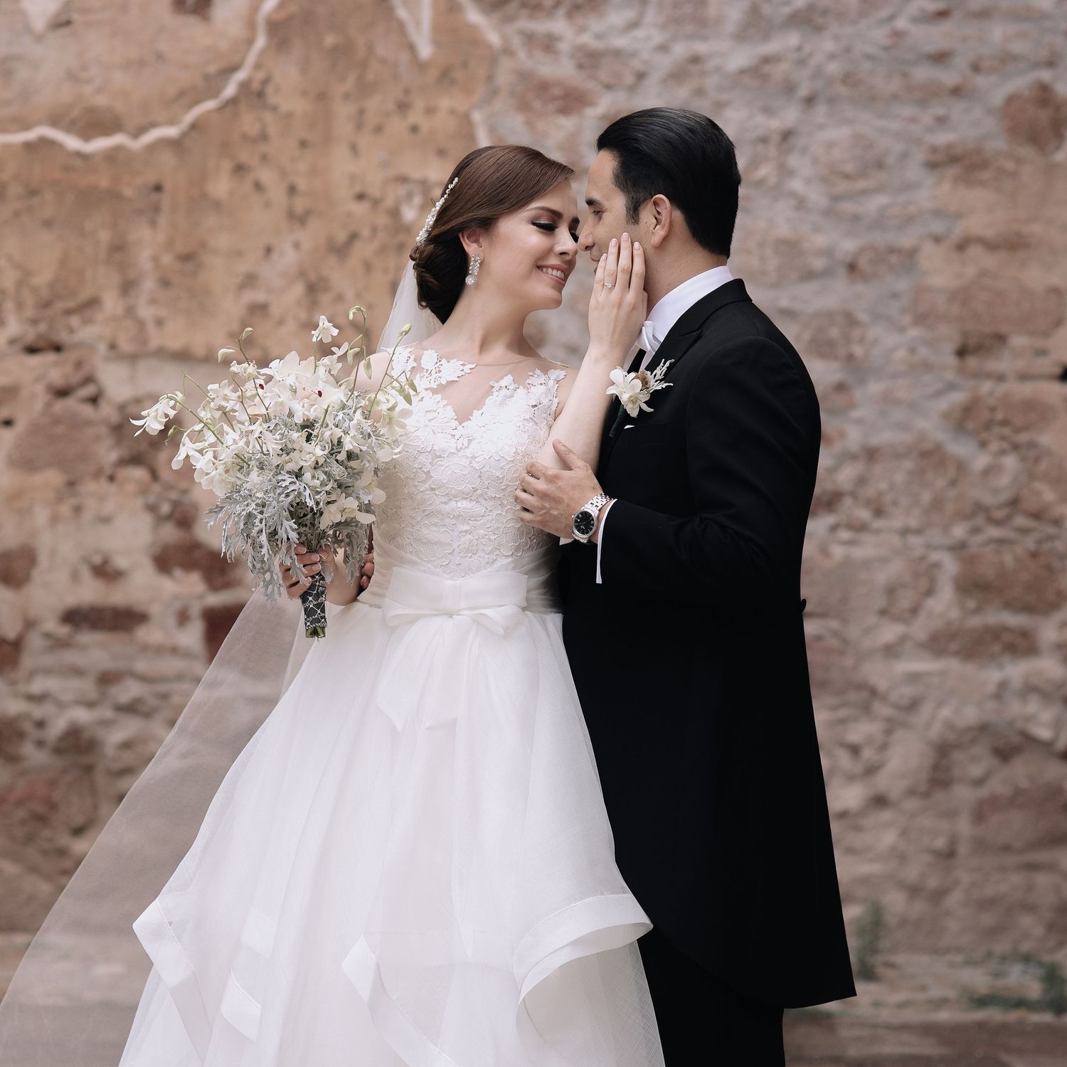 Bride and groom share intimate moments against a rustic stone wall backdrop.