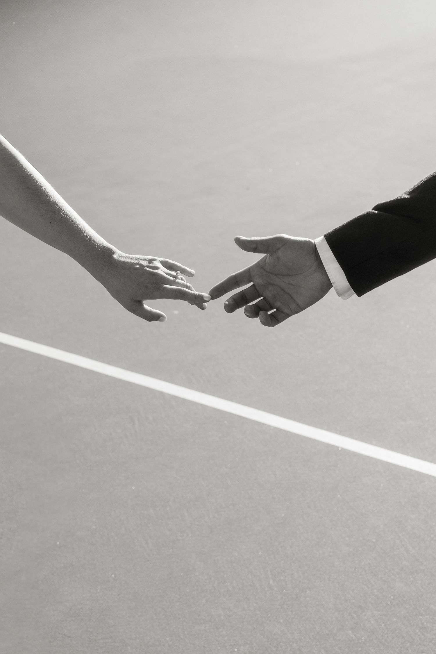 A series of black and white photographs showing hands reaching towards diagonal white lines against a gray background.