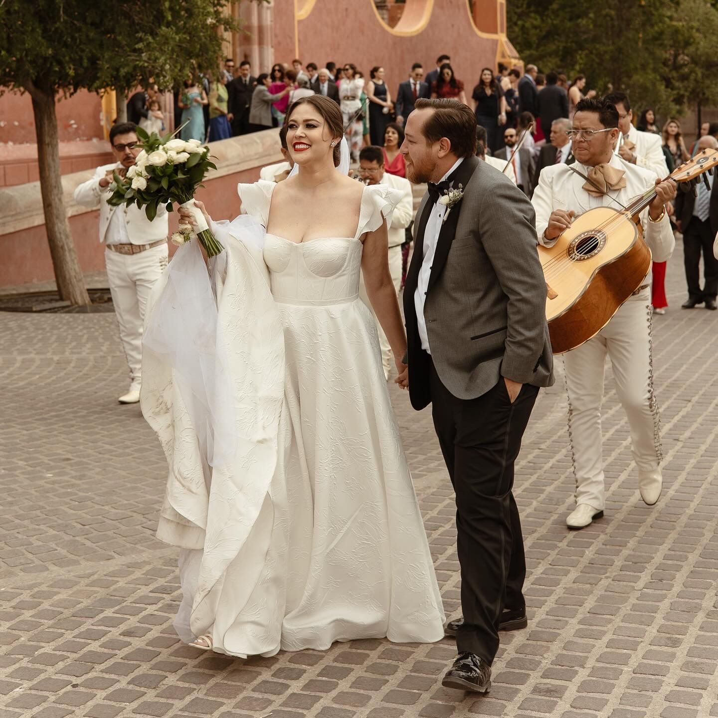 Wedding celebration with musicians playing in a traditional Mexican courtyard.