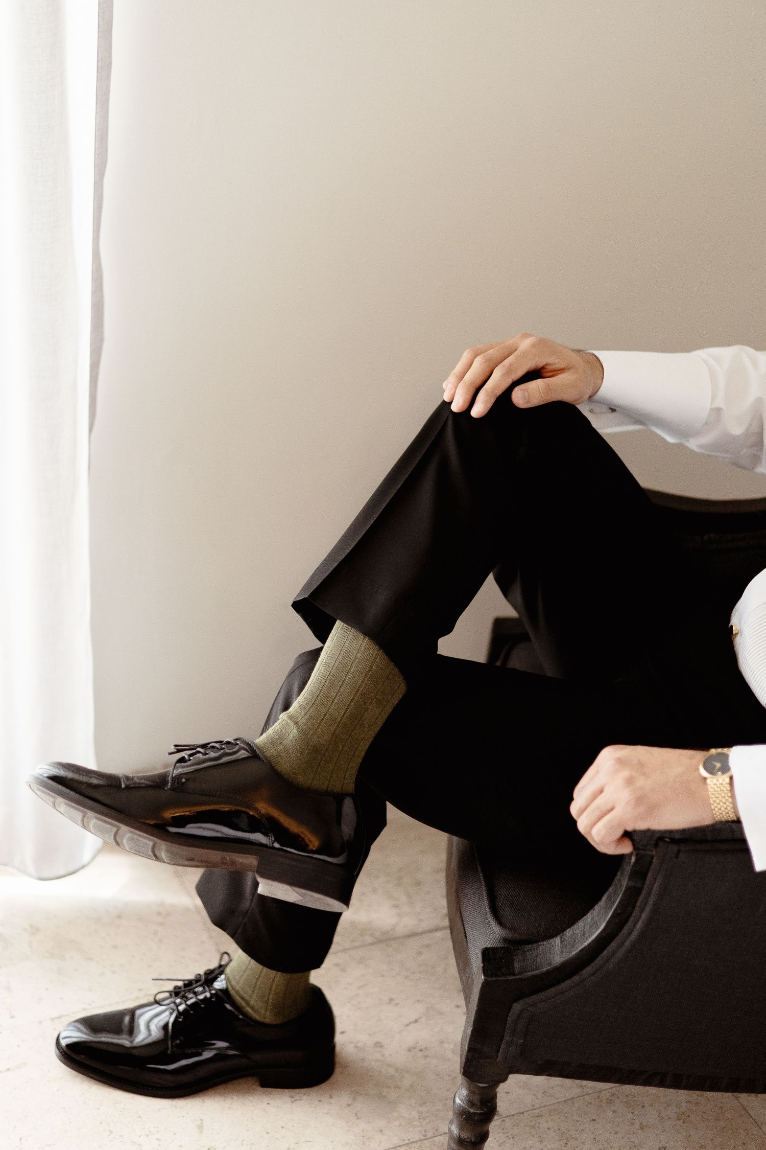 Four sequential images showing someone putting on black leather dress shoes with gray socks and black pants.