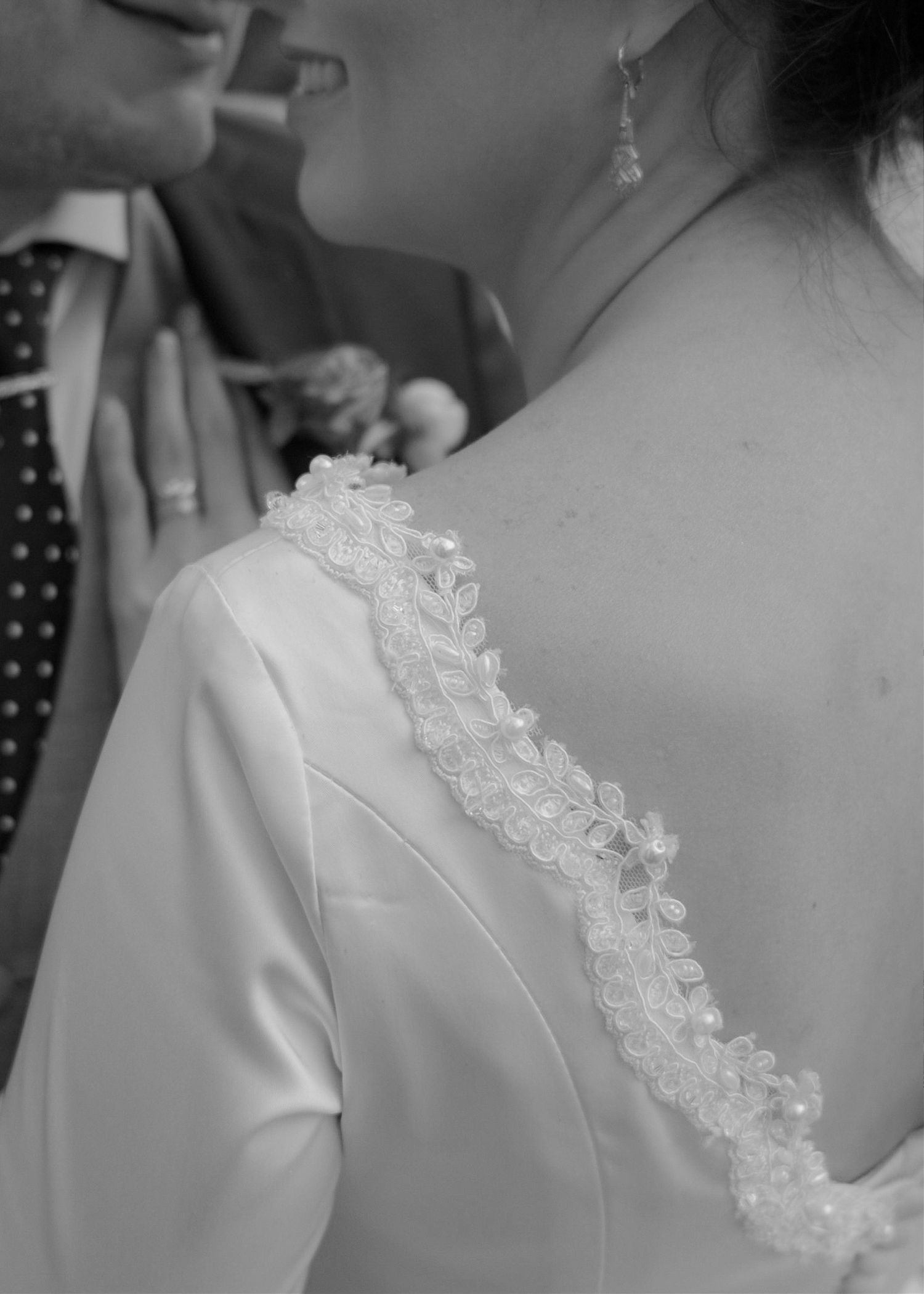 Detail shot of intricate lace trim on wedding dress in black and white.