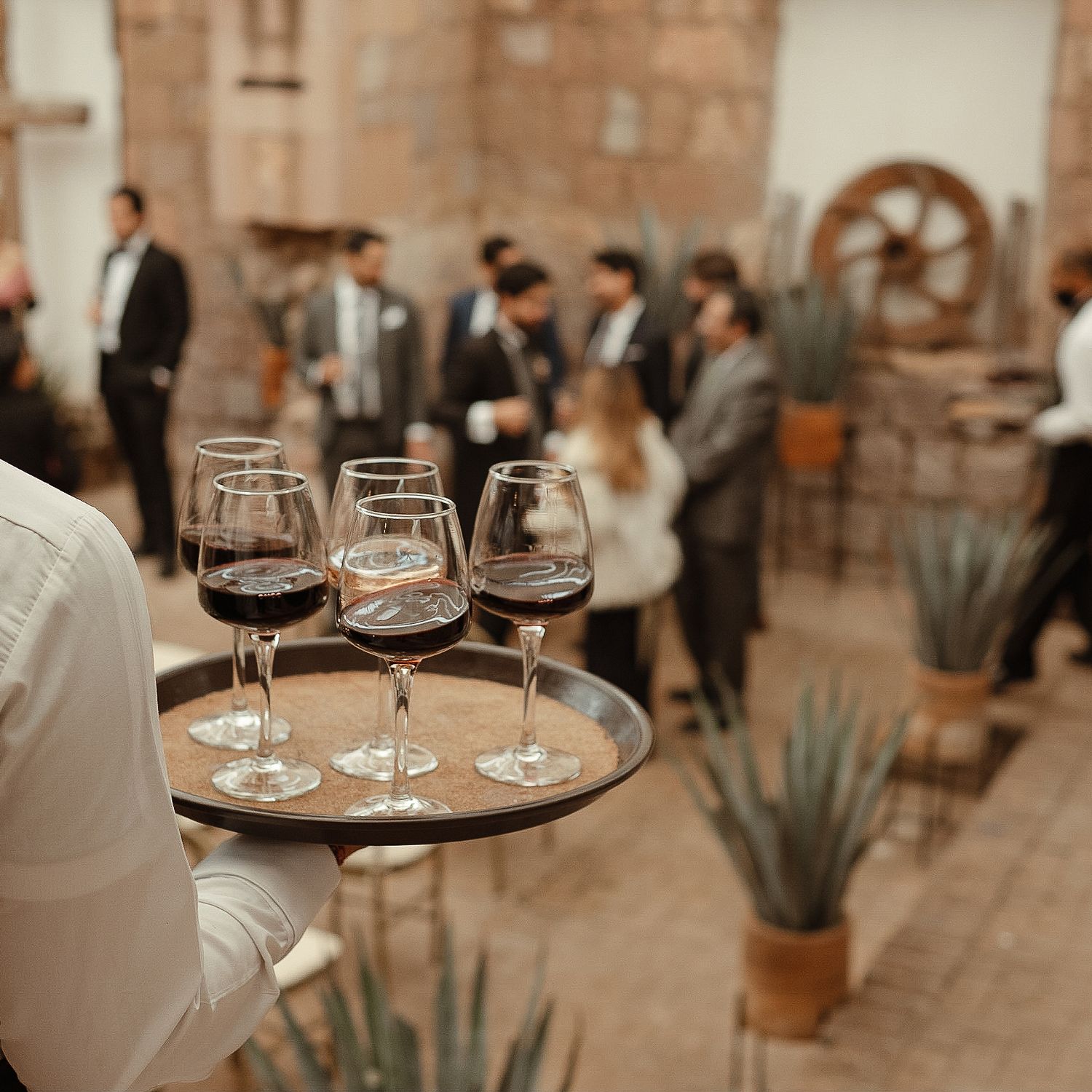 Wine glasses arranged on wooden serving trays at an elegant outdoor wedding reception.