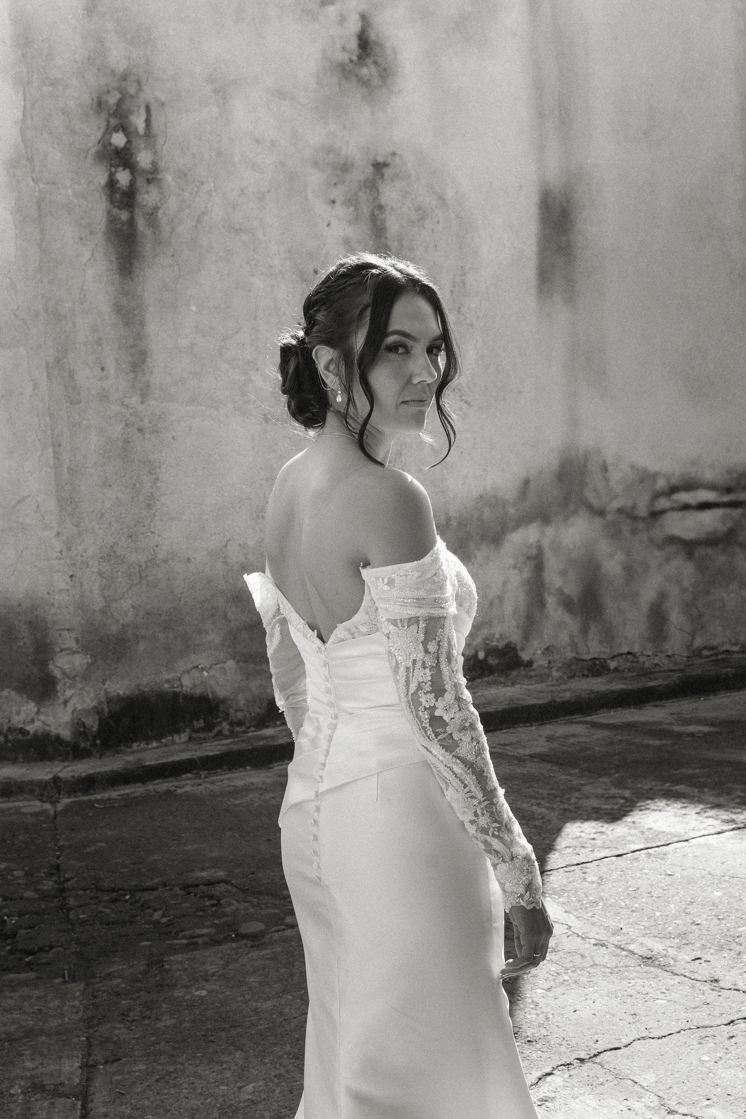 Black and white portrait of bride in lace off-shoulder wedding gown.