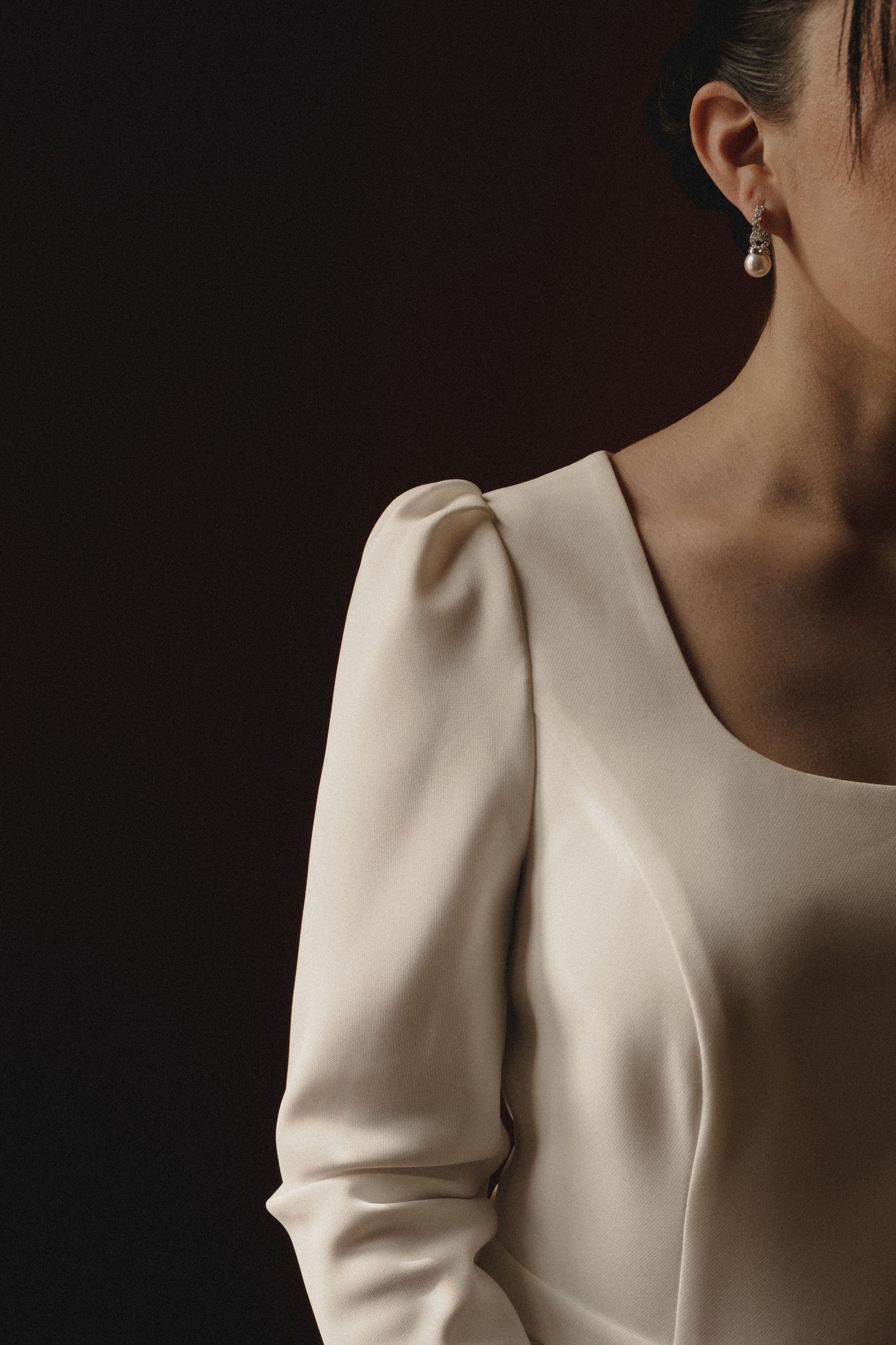 A series of cropped fashion photographs showing details of a white structured blazer with dramatic shoulder design.