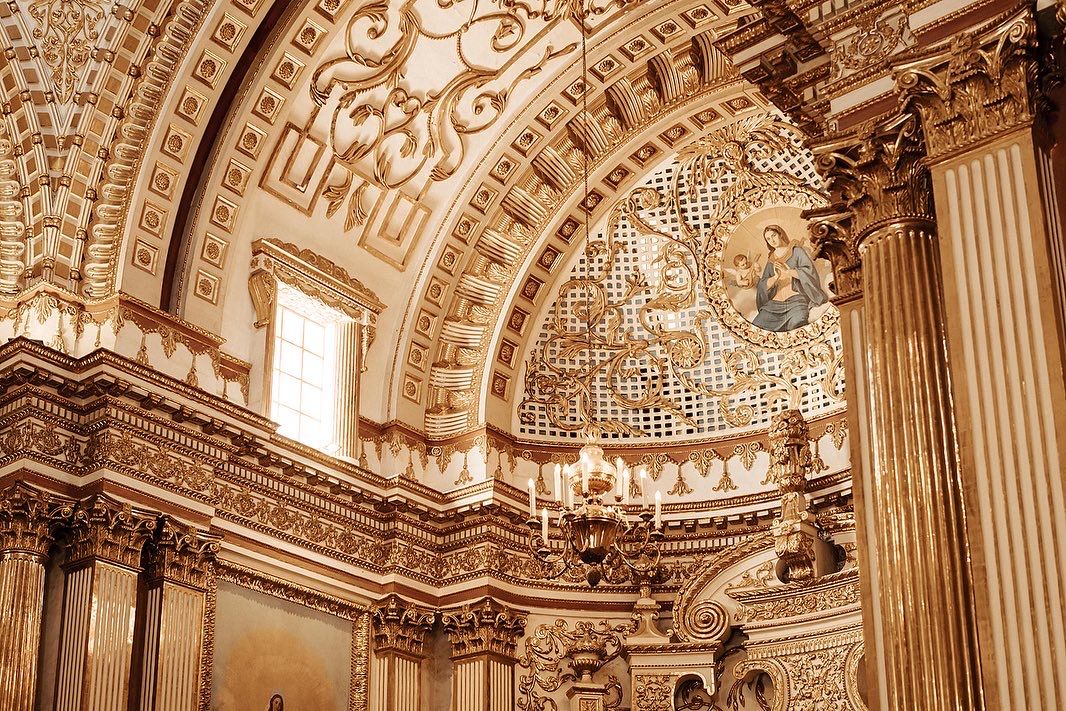 Ornate baroque cathedral ceiling with intricate gold details and architectural flourishes.