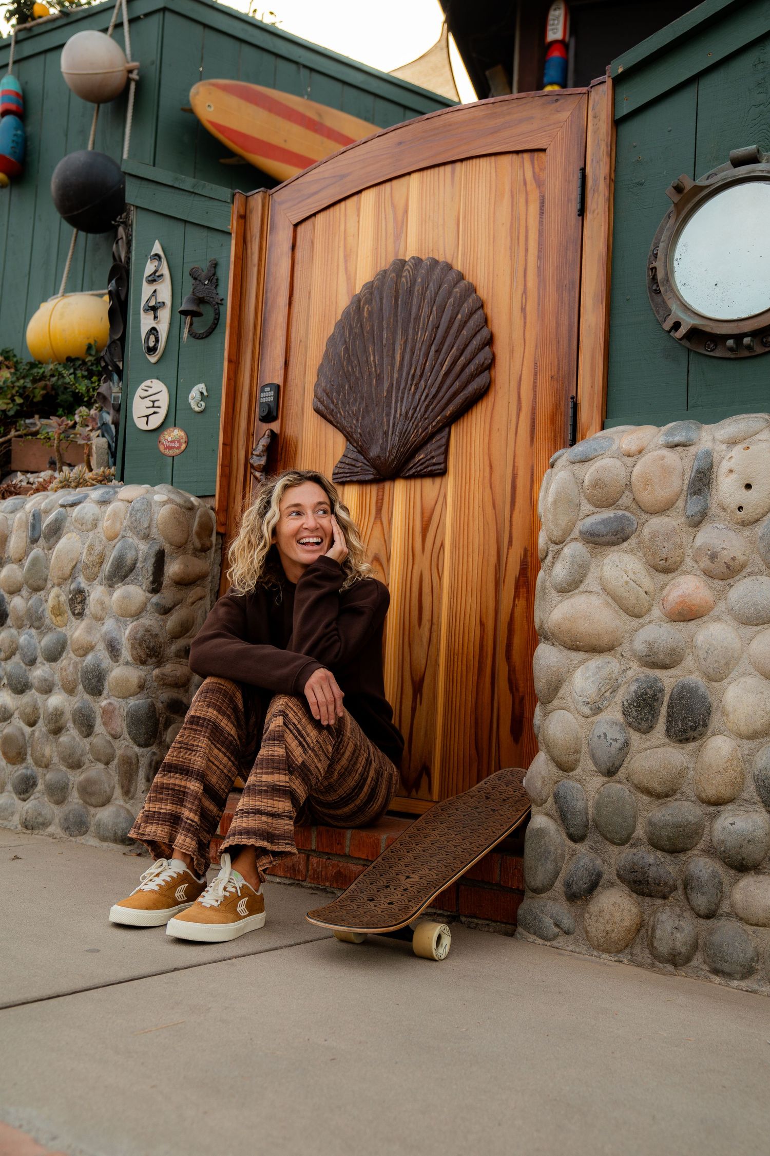 Girl sitting in front of a beach house in Volcom apparel, showcasing bold style and dynamic movement on a sunny day.
