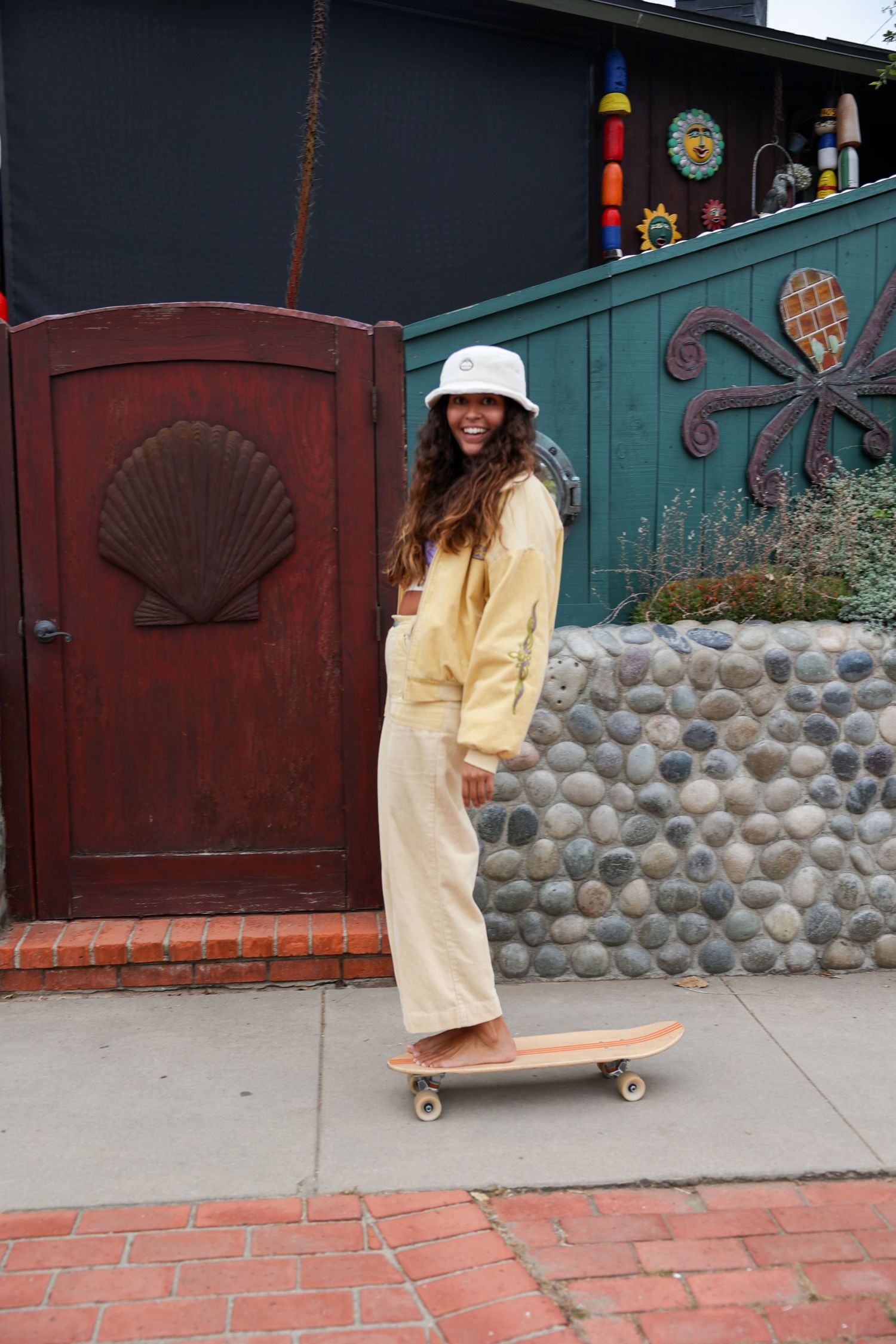 Girl wearing a yellow outfit, enjoying a sunny day while skateboarding with a carefree vibe, promoting Sunbum sunscreen.