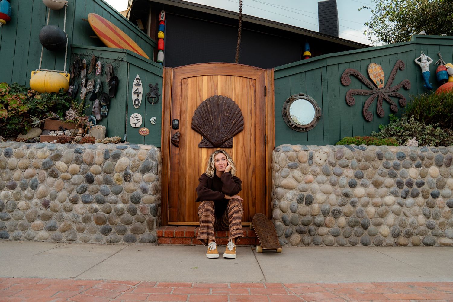 Girl sitting in front of a beach house in Volcom apparel, showcasing bold style and dynamic movement on a sunny day.