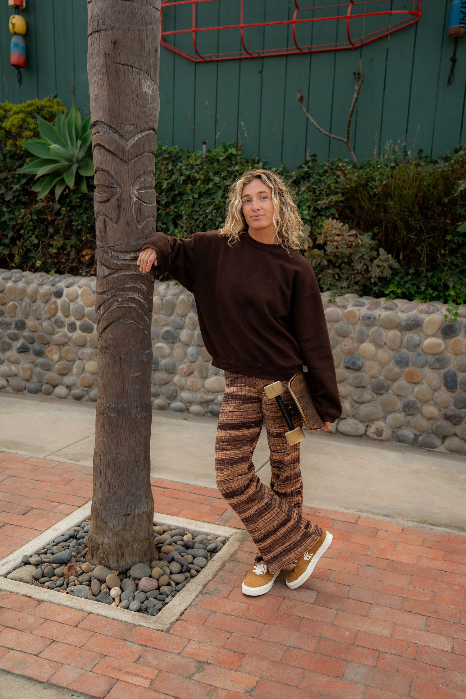 Girl standing against a tree in Volcom apparel, showcasing bold style and dynamic movement on a sunny day.