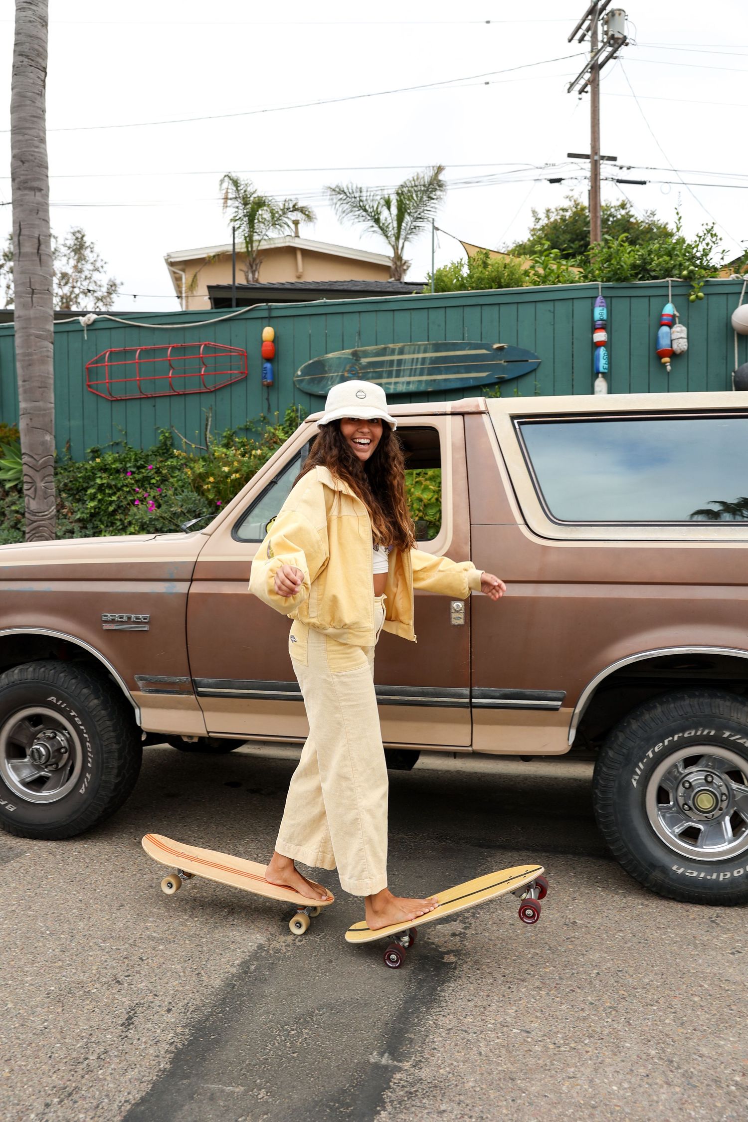 Girl wearing a yellow outfit, enjoying a sunny day while skateboarding with a carefree vibe, promoting Sunbum sunscreen.