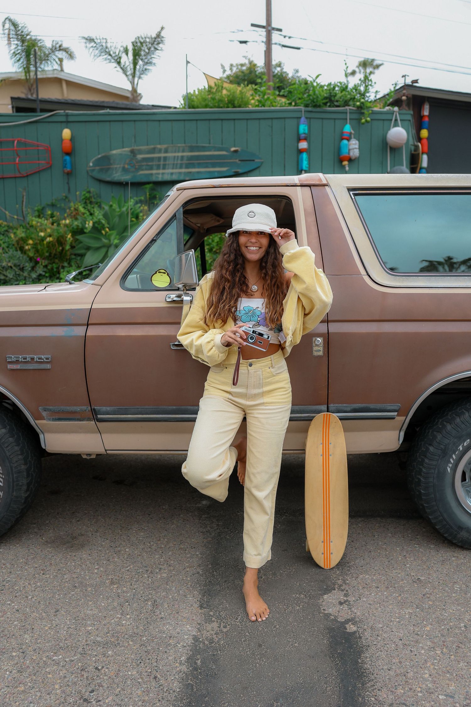 Girl wearing a yellow outfit, enjoying a sunny day while skateboarding with a carefree vibe, promoting Sunbum sunscreen.