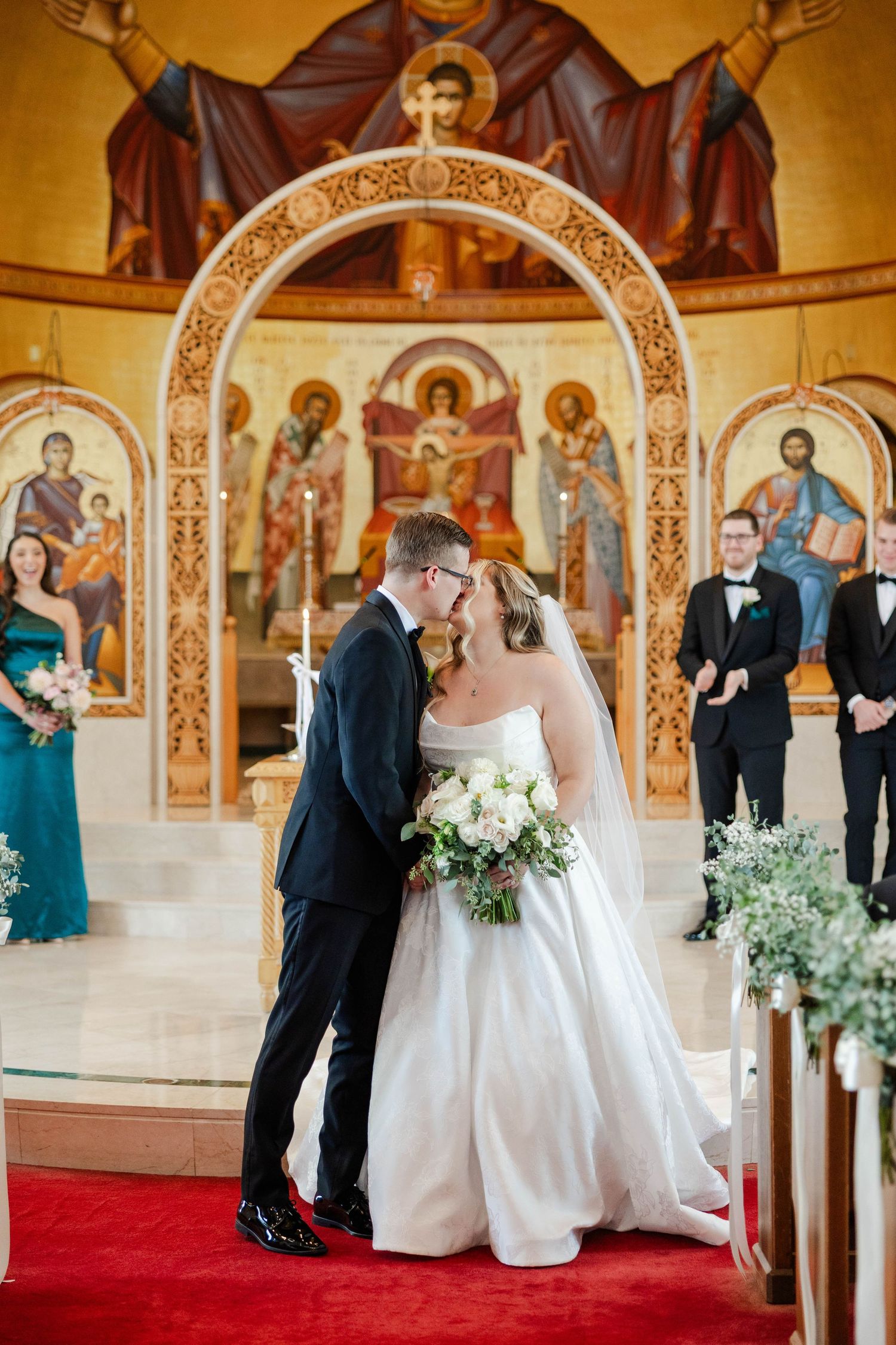 Wedding ceremony taking place in an ornate Orthodox church with religious icons and a decorative arch.