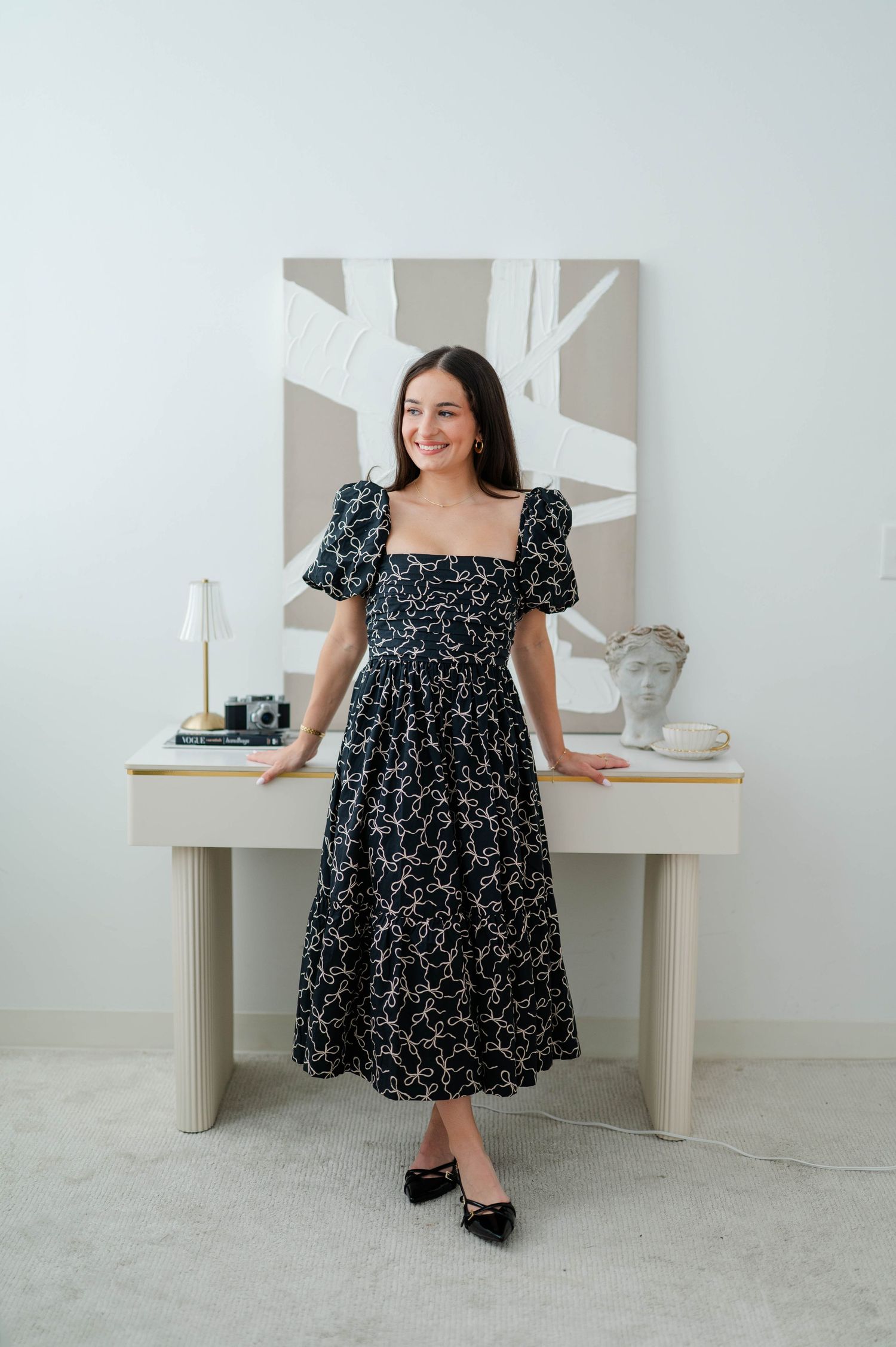 A black floral babydoll dress with puff sleeves is modeled against a white studio backdrop.