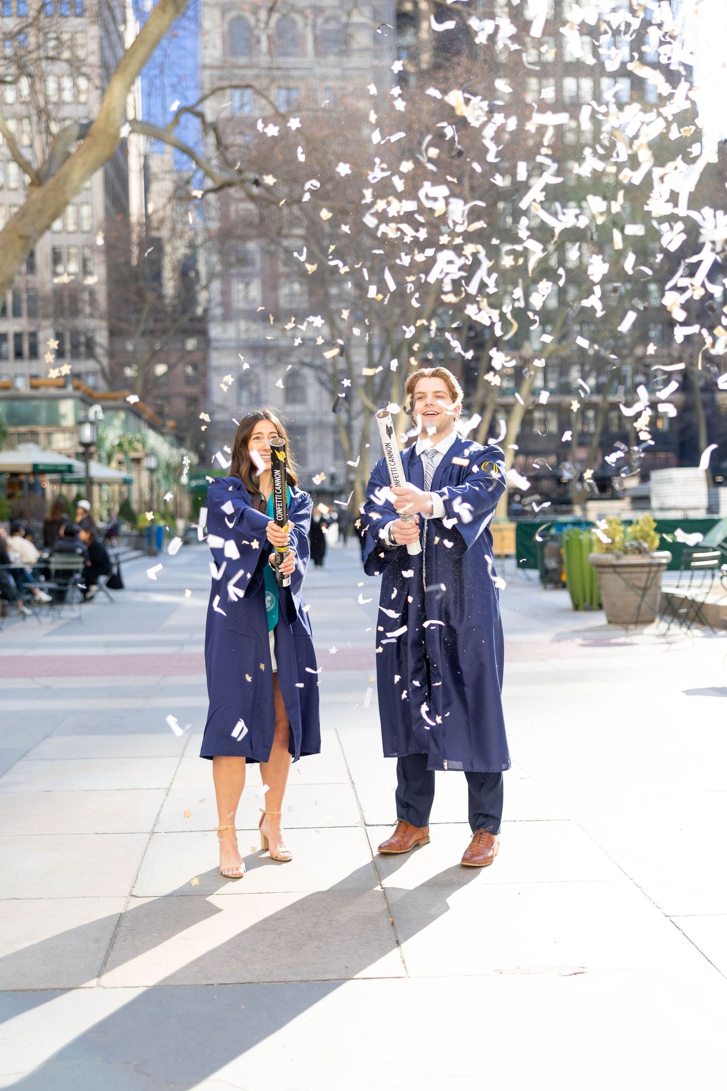 Two people celebrating with confetti flying around them in an outdoor urban setting.