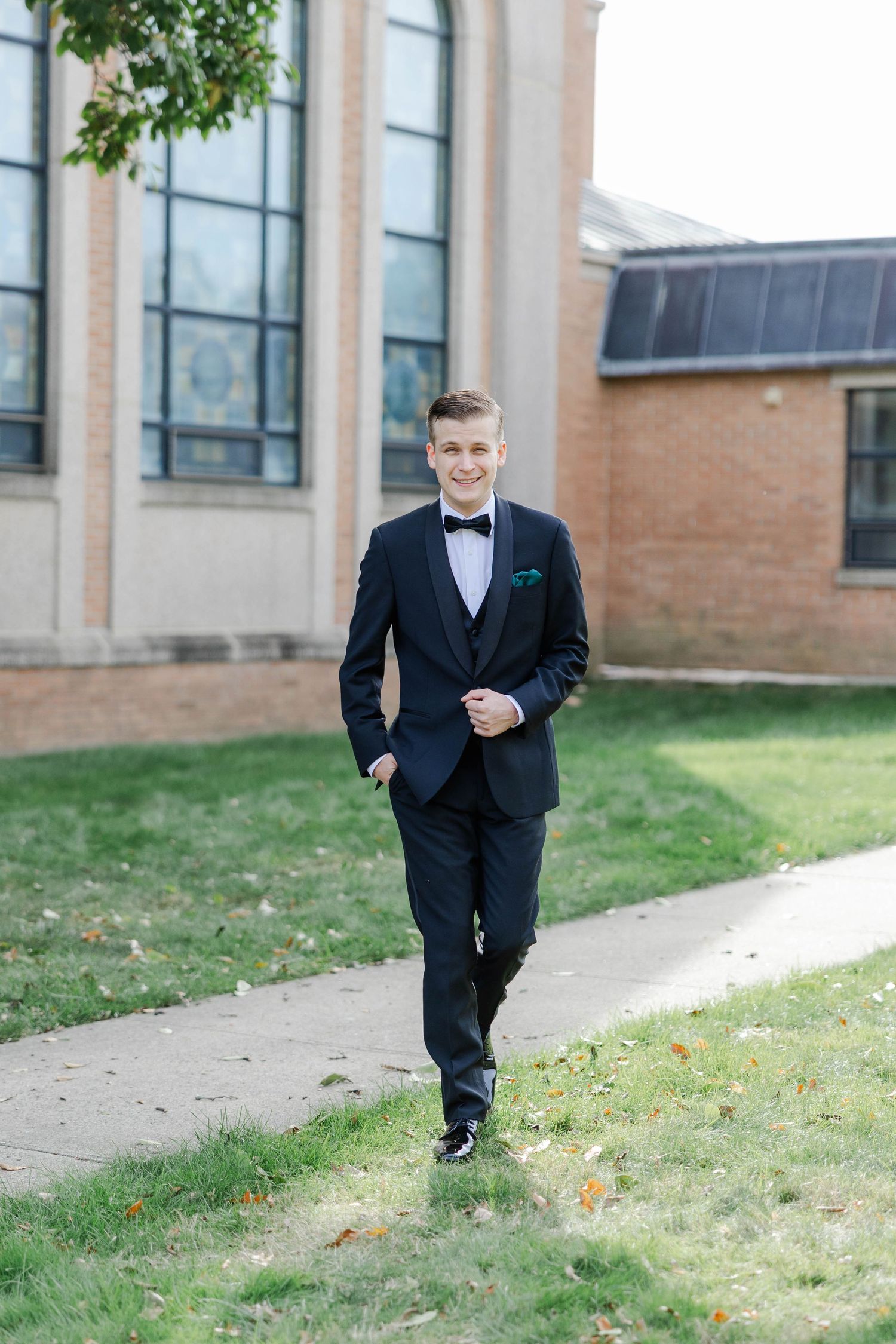 A sequence of four photos showing someone in a black tuxedo running joyfully on a sidewalk near a brick building.