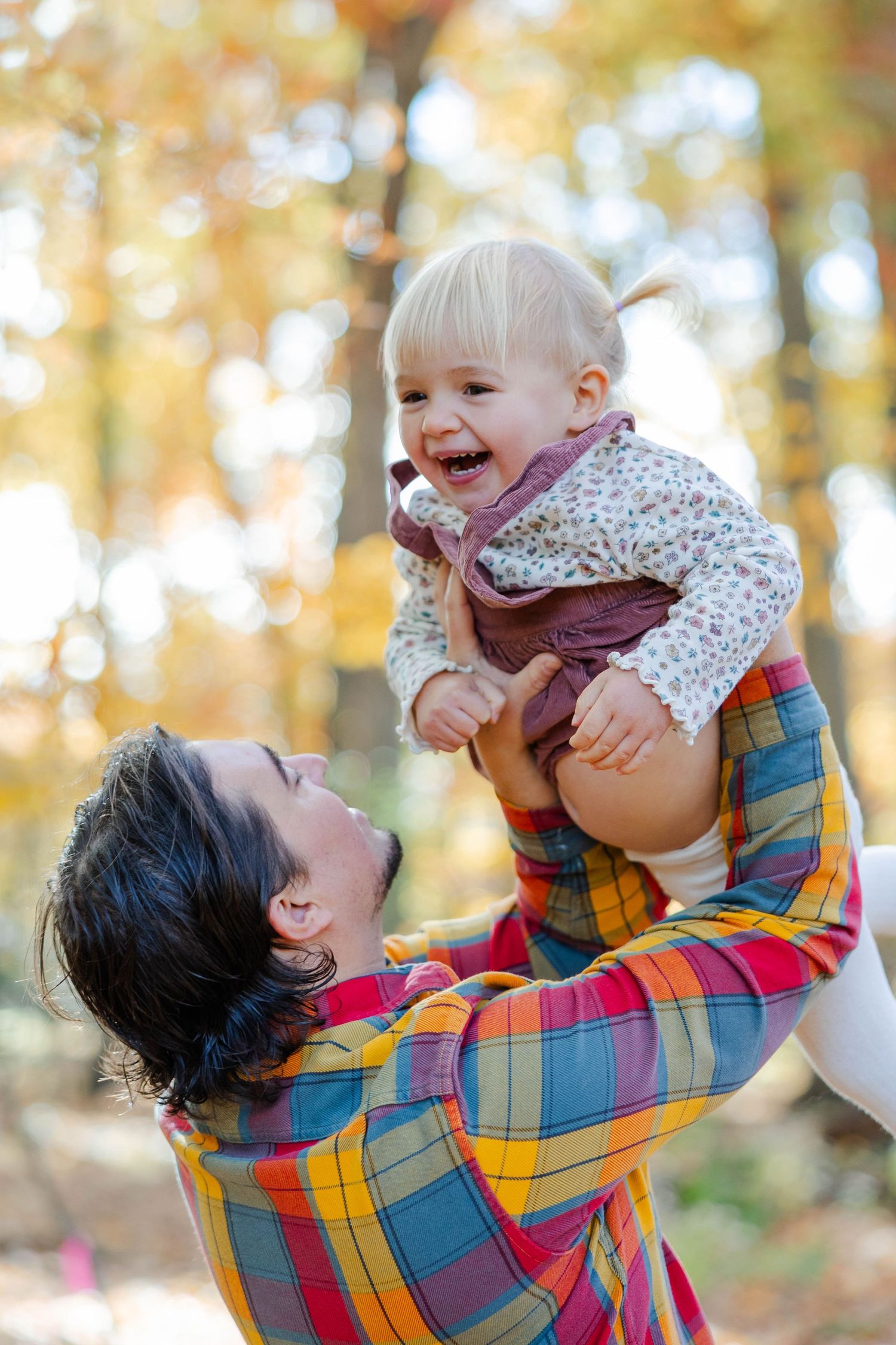 A joyful moment captured outdoors in autumn with colorful plaid shirt and falling leaves in the background.