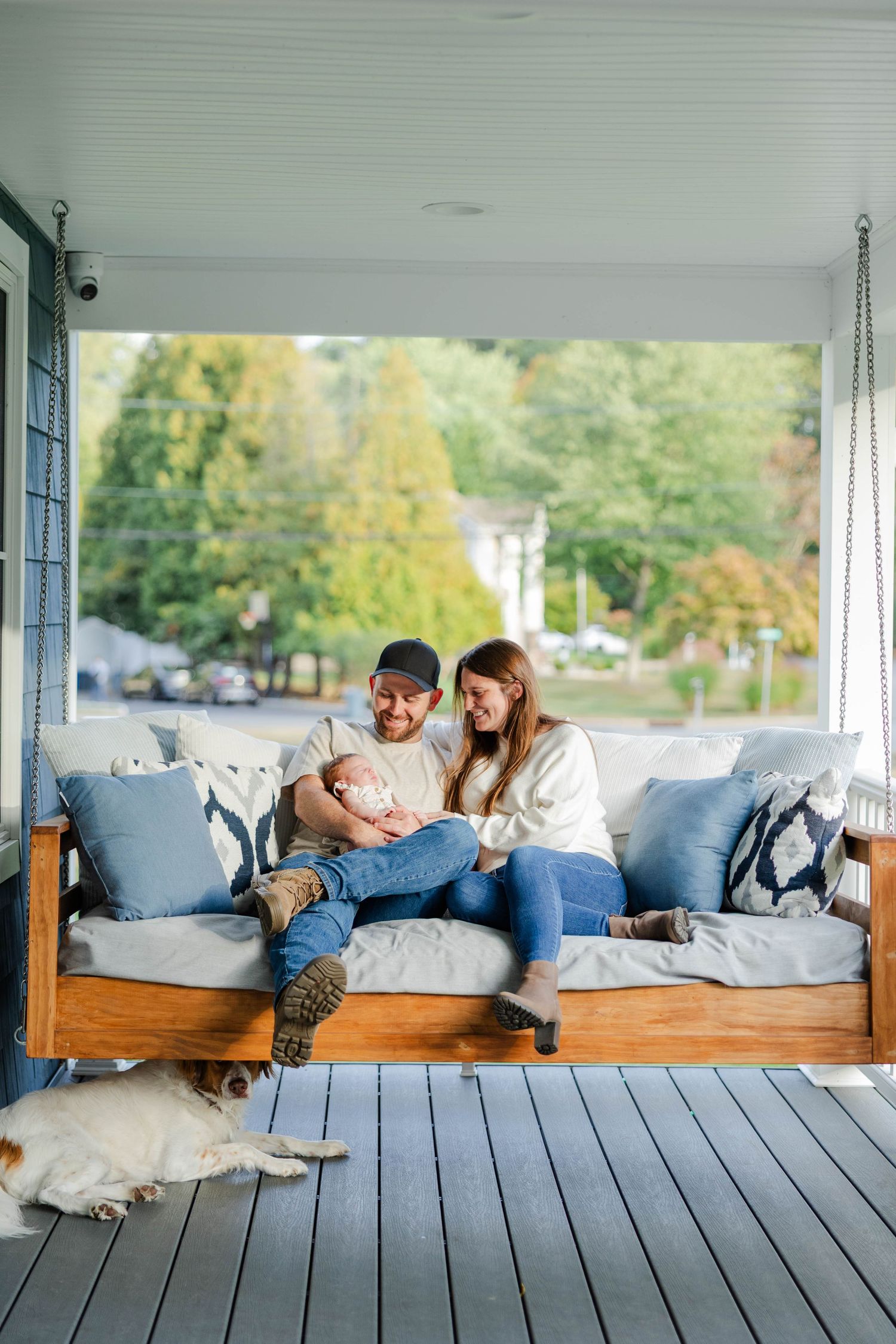 A cozy scene on a porch swing with blue cushions and wooden deck on a sunny autumn day.