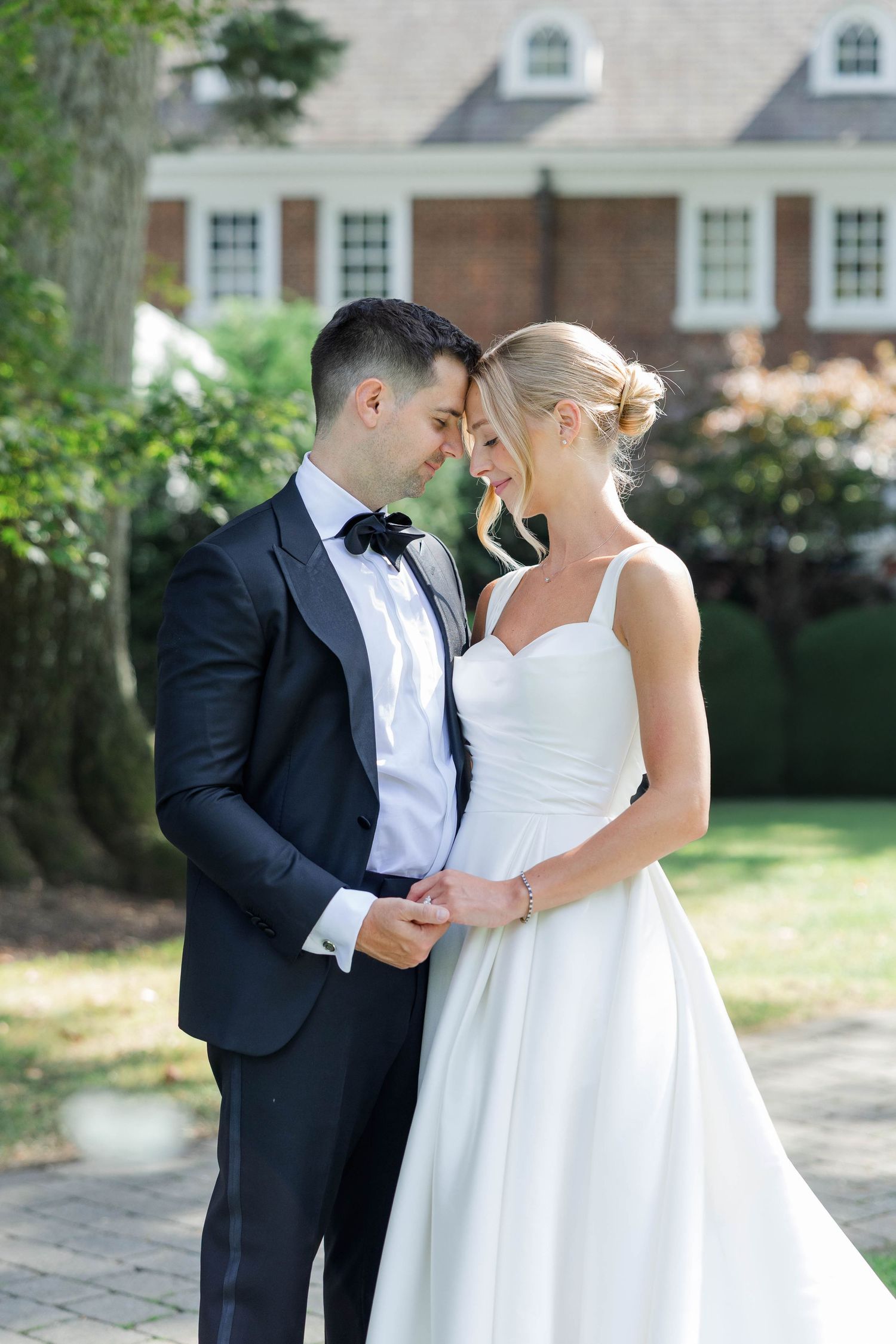 A romantic moment between newlyweds in formal attire sharing a tender embrace outdoors on their wedding day.