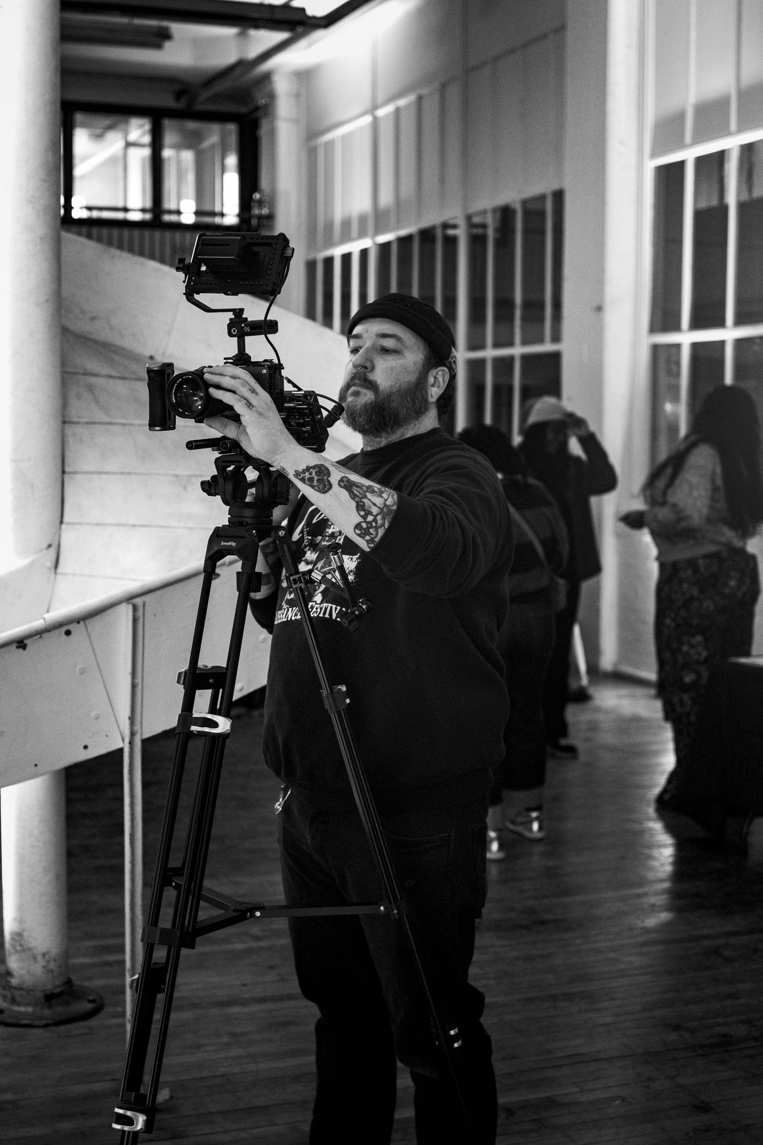 A sequence of black and white photos showing a person bending down to adjust camera equipment in a hallway.