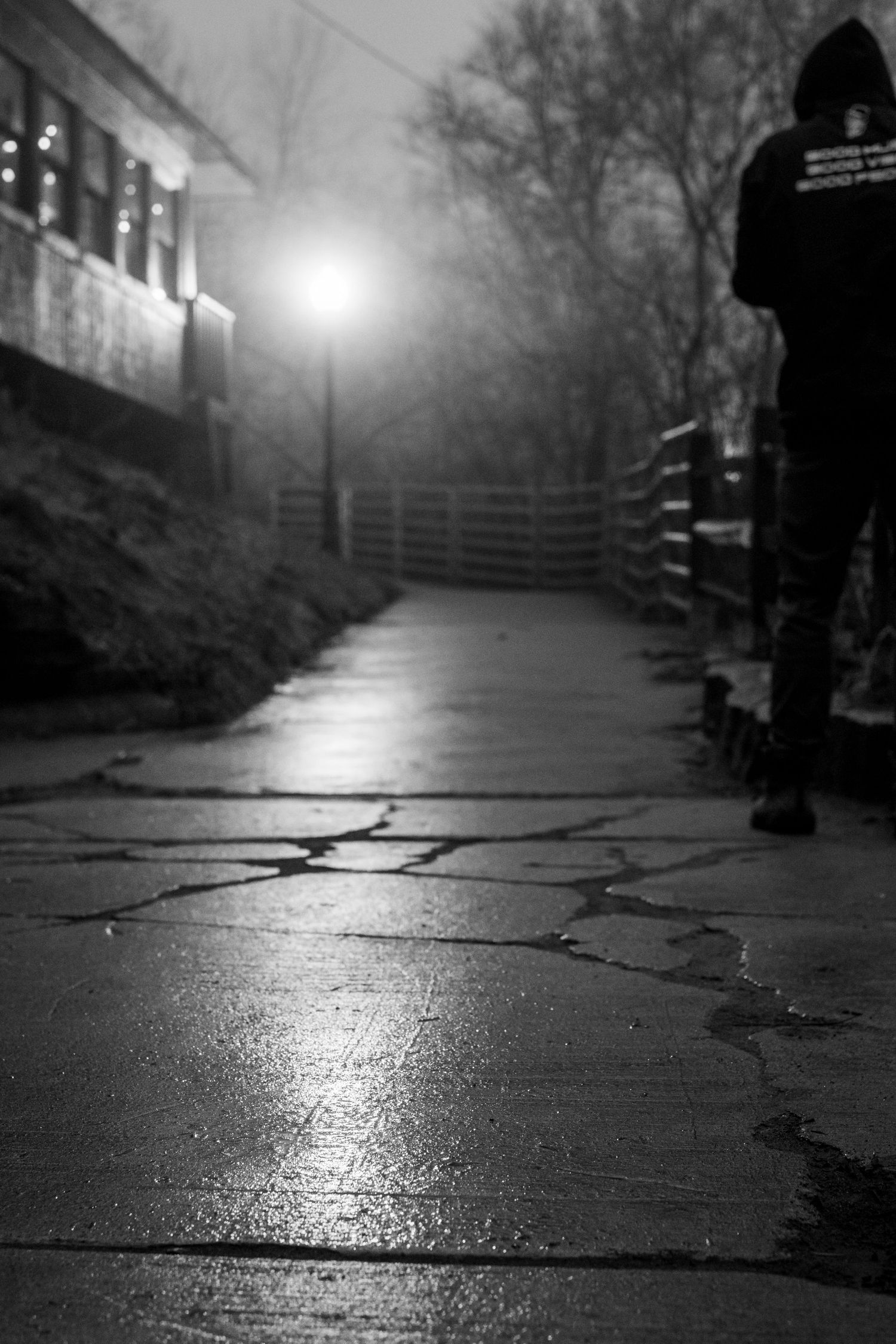 Wet cobblestone path at night with glowing streetlight in the distance.