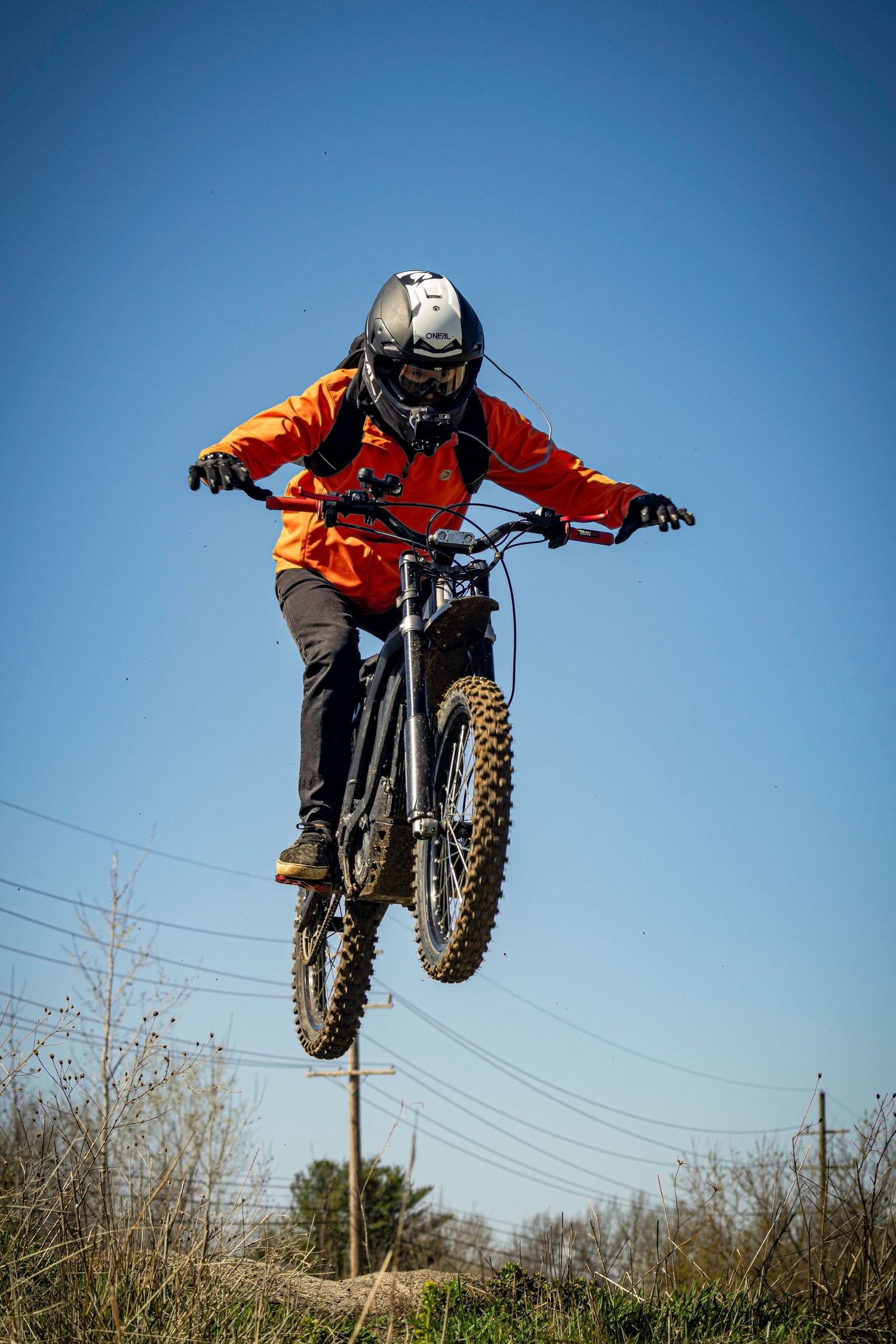 Motocross rider performing jump on dirt bike against clear blue sky.