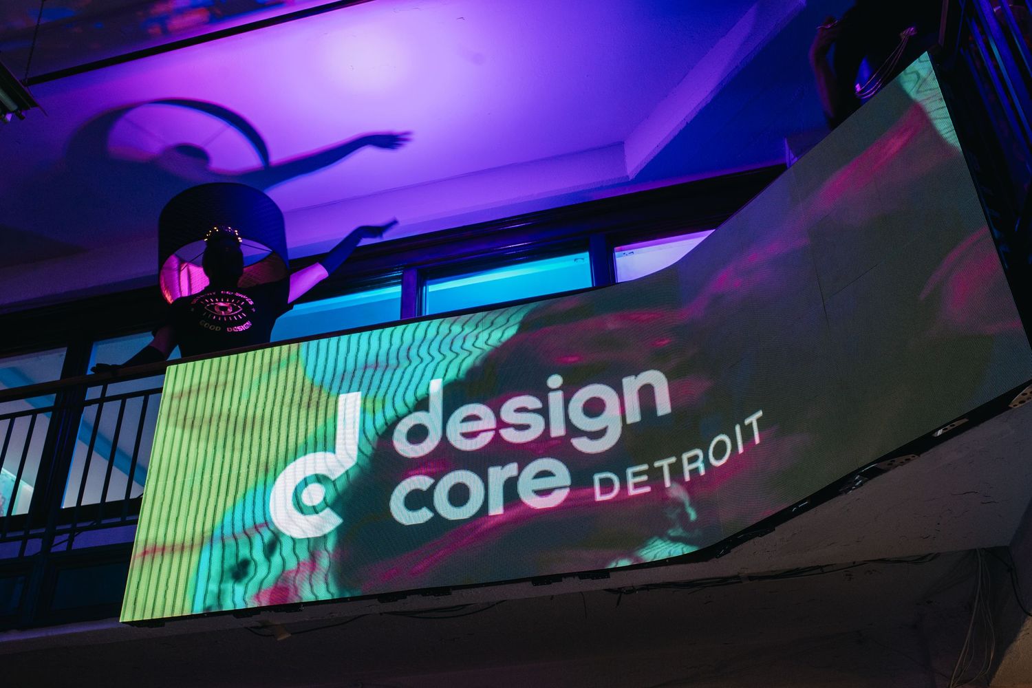 Neon signs and digital displays illuminate a dark venue with purple and green lighting effects.