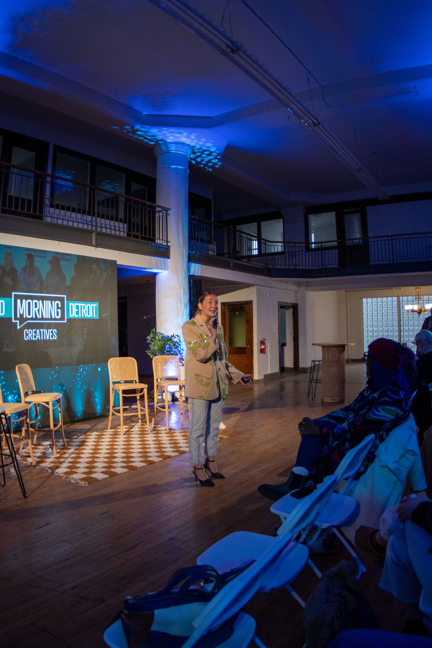 A dark room illuminated with blue lighting showcases a black and white checkered floor and scattered furniture.