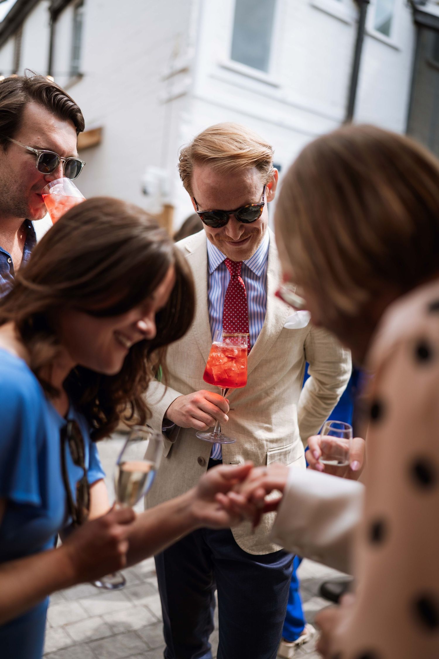 A group of people in formal attire lean in close together while examining something with curiosity and interest.