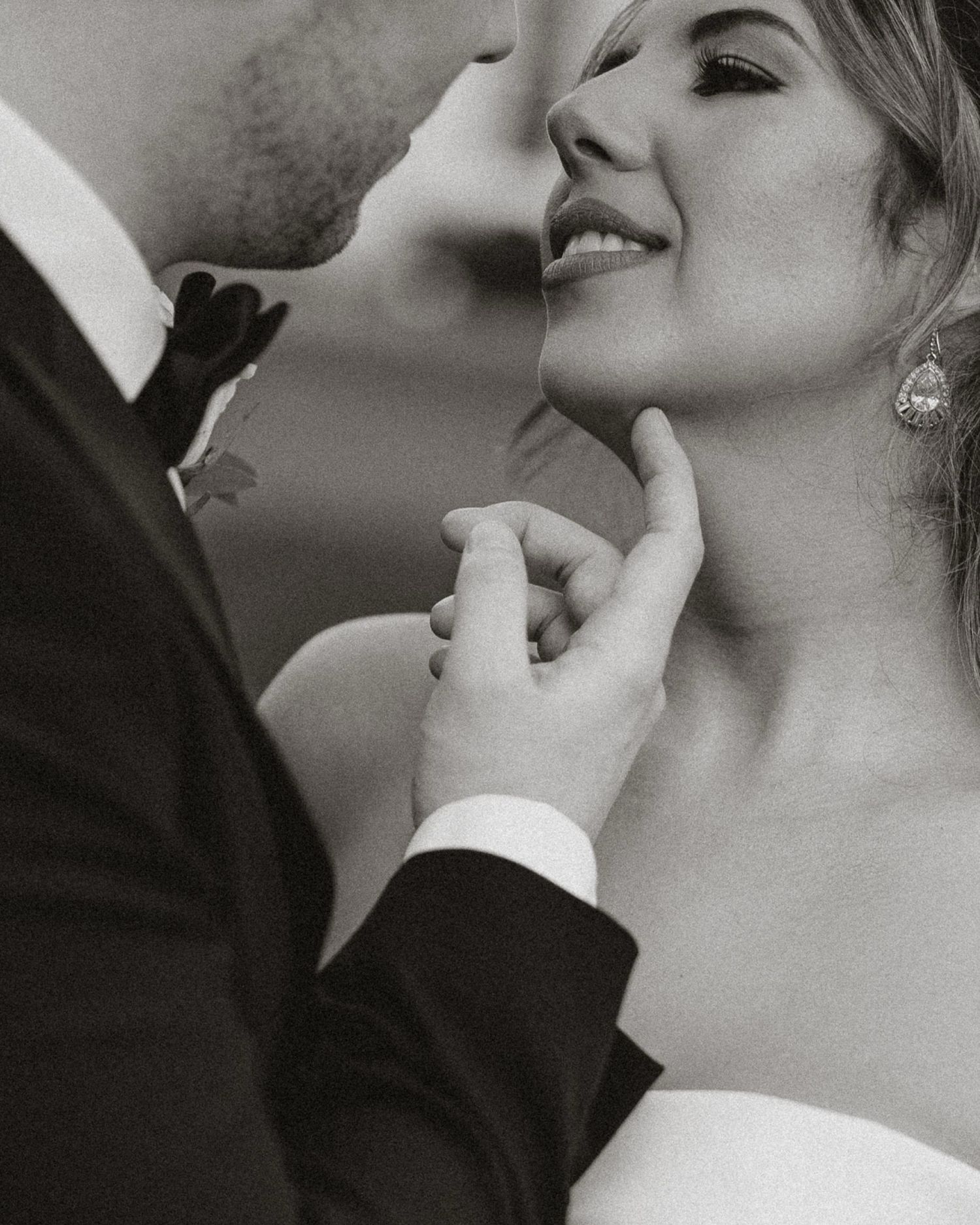 Intimate black and white close-up of a romantic couple sharing a tender moment in wedding attire.