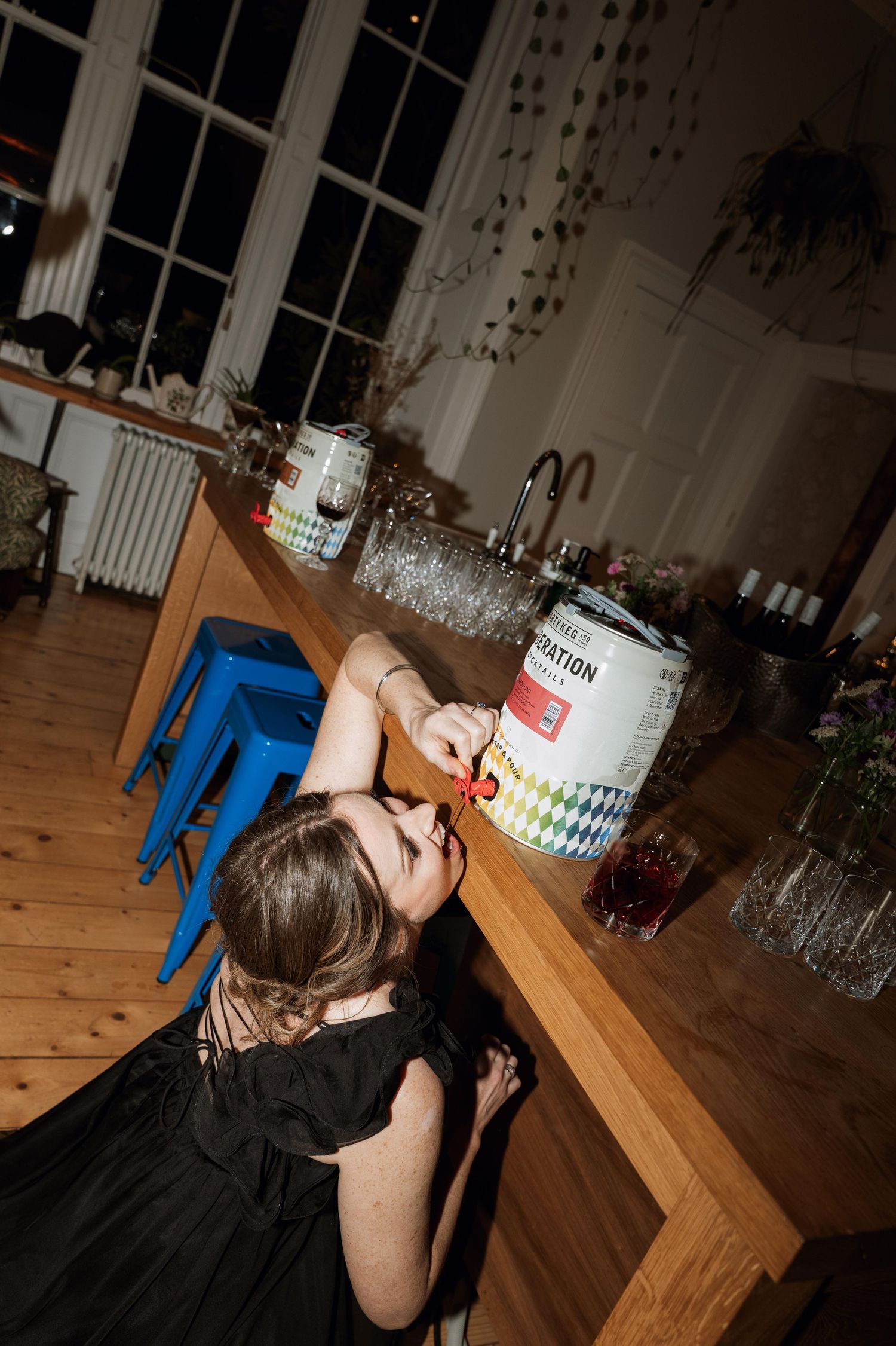 A person in a dark dress leans over a wooden table at what appears to be a party or celebration.