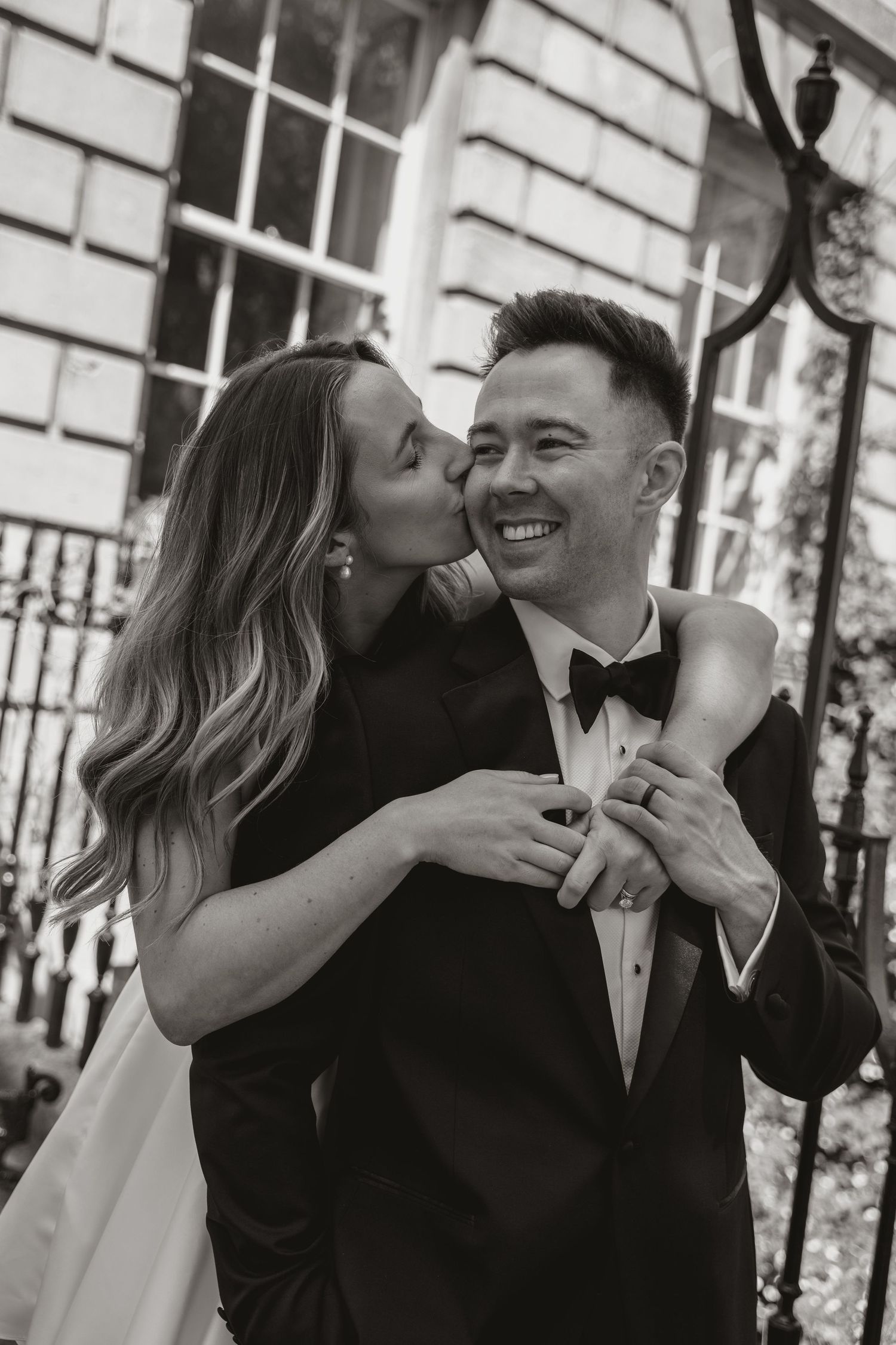 A sequence of black and white photos showing a couple sharing intimate kisses and embraces at an elegant venue.