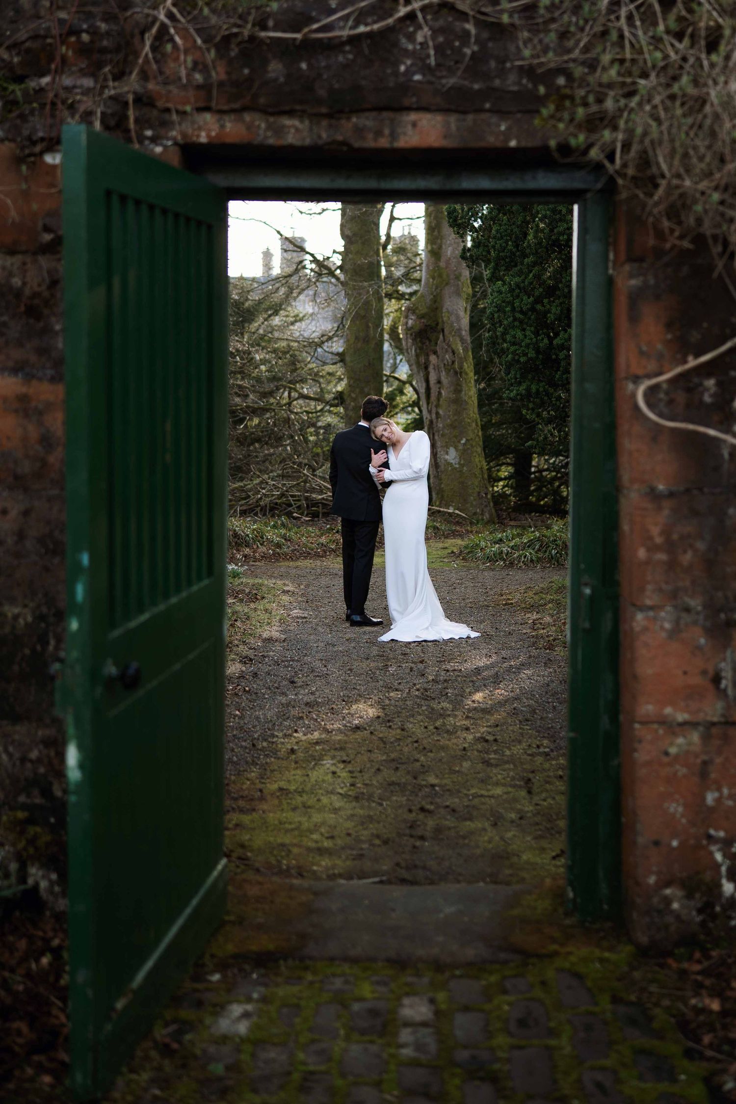 A series of four wedding photos showing a couple in formal attire posing against a rustic brick wall and green gate.