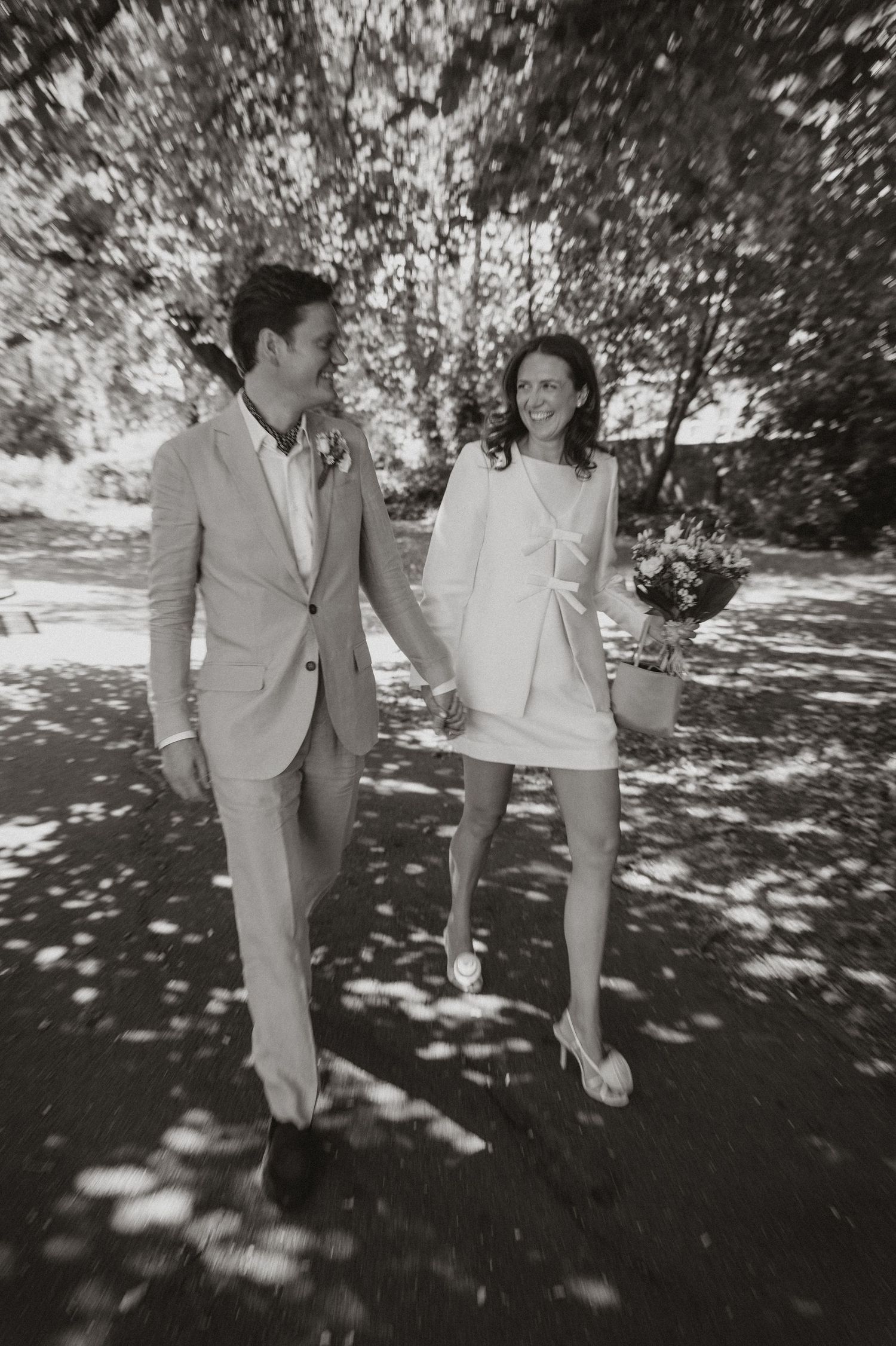A sequence of black and white photographs showing people walking together in dappled sunlight beneath trees.