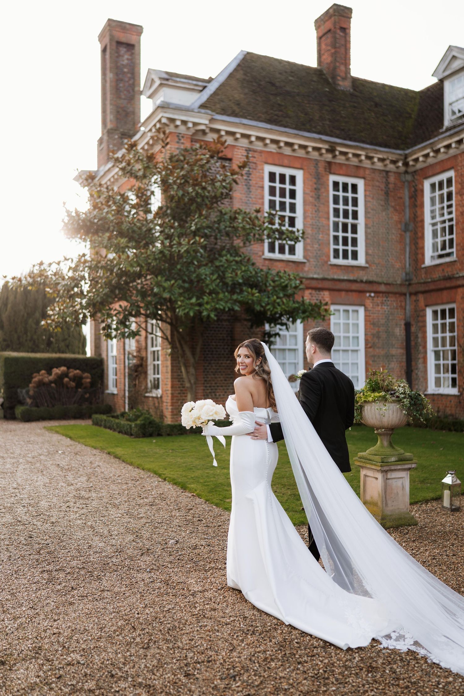 couple holding hands walking in front of gosfield hall wedding venue on their wedding day