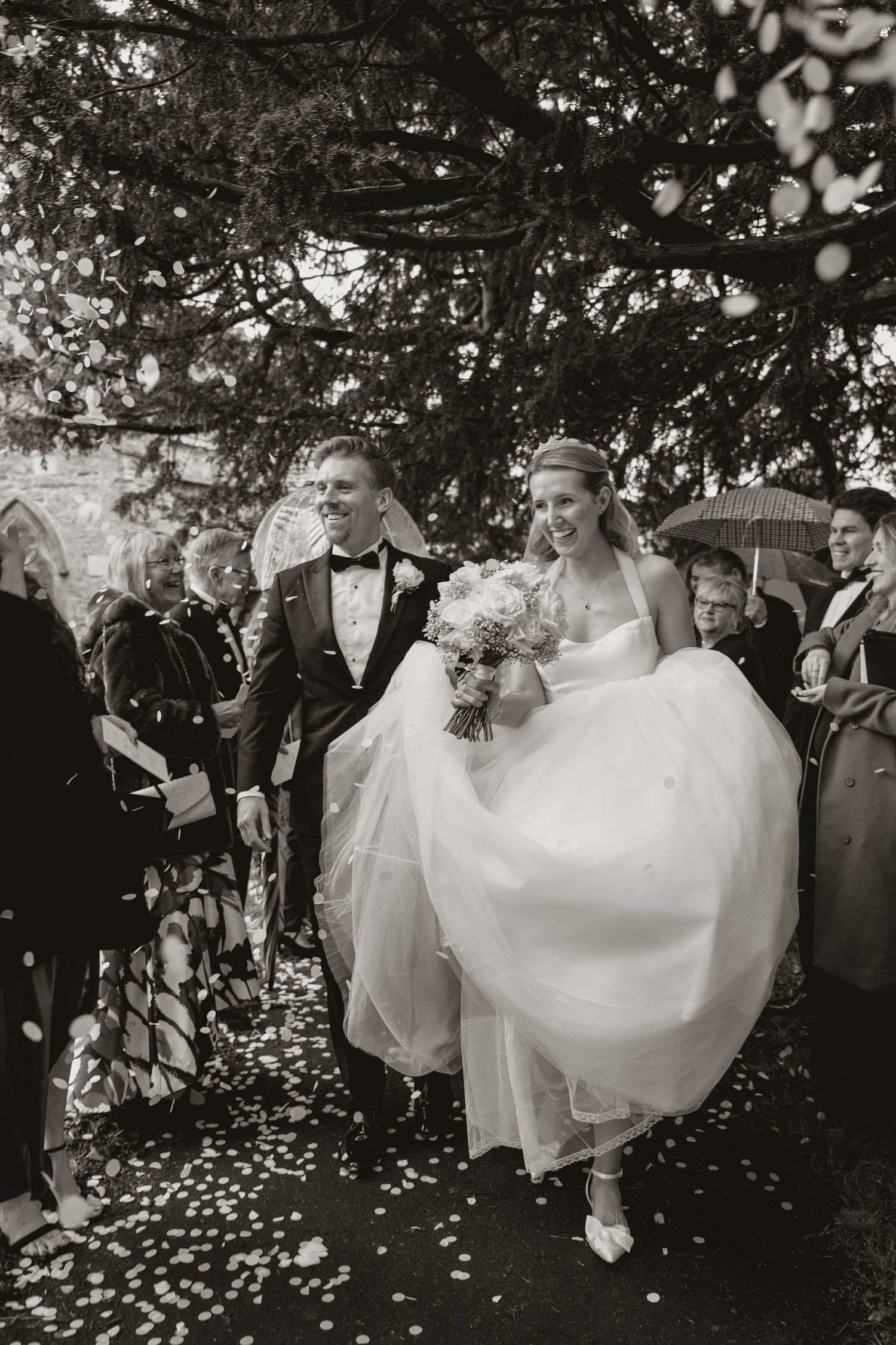 A joyful wedding celebration sequence shows the couple walking through a shower of flower petals under tree branches.
