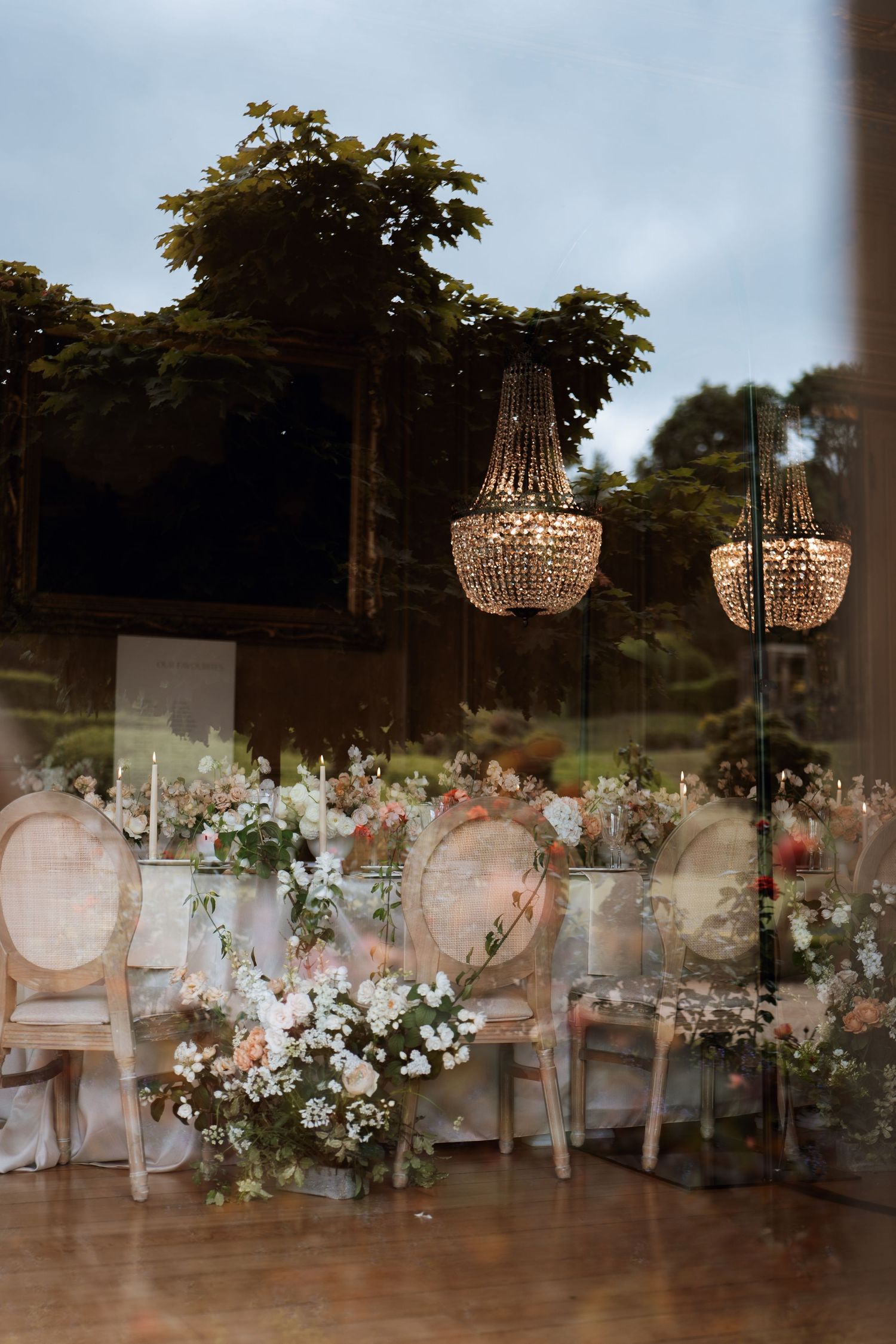 Elegant wedding reception setup with crystal chandeliers and white floral arrangements creating a romantic atmosphere.