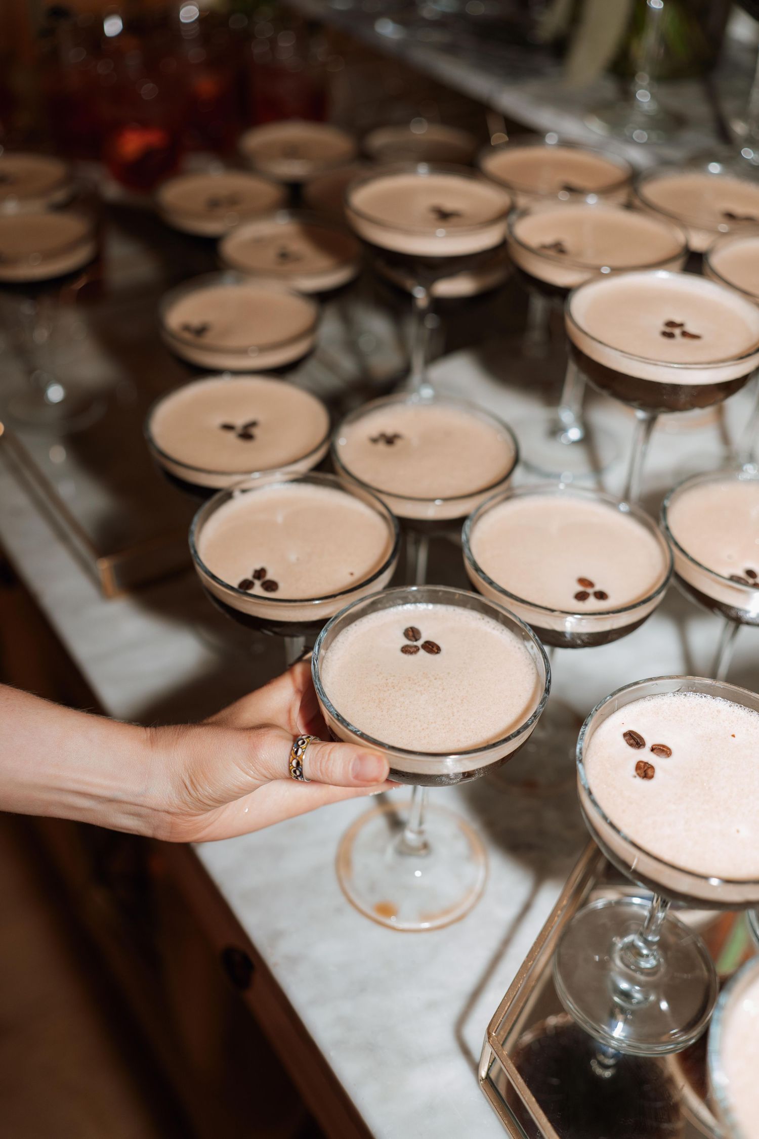 A row of elegant cocktail glasses filled with creamy espresso martinis topped with coffee beans for garnish.
