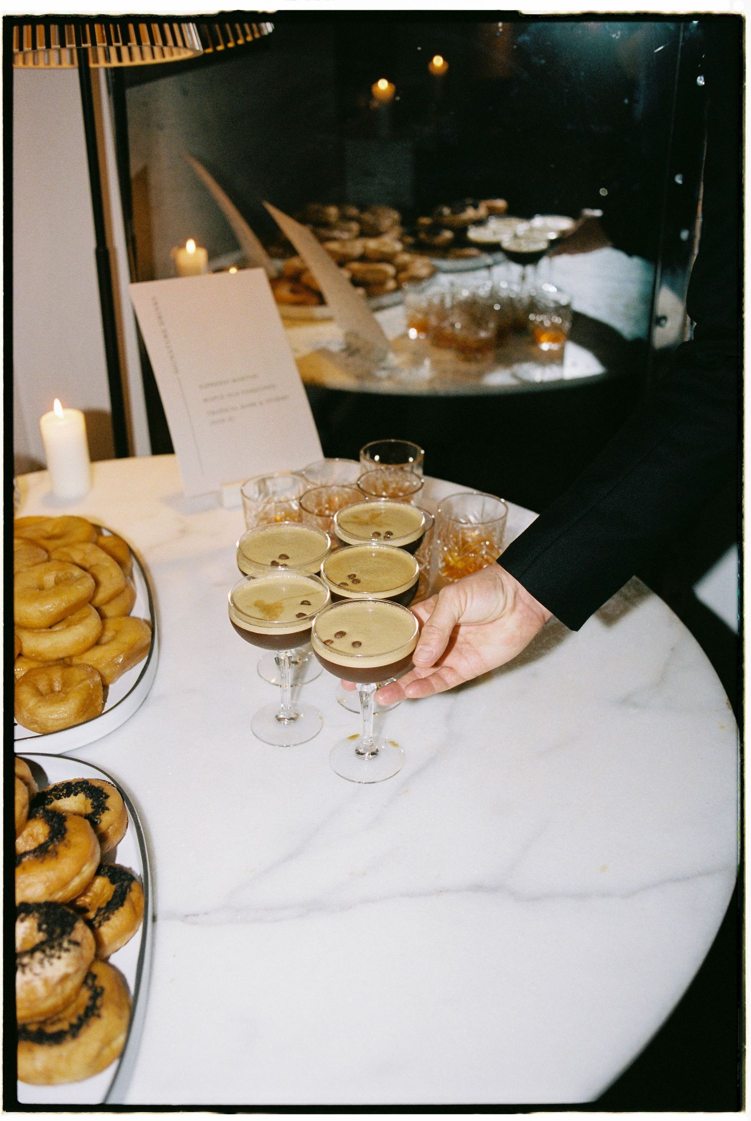 Champagne glasses and appetizer plates arranged on white tablecloths in a dimly lit restaurant setting.