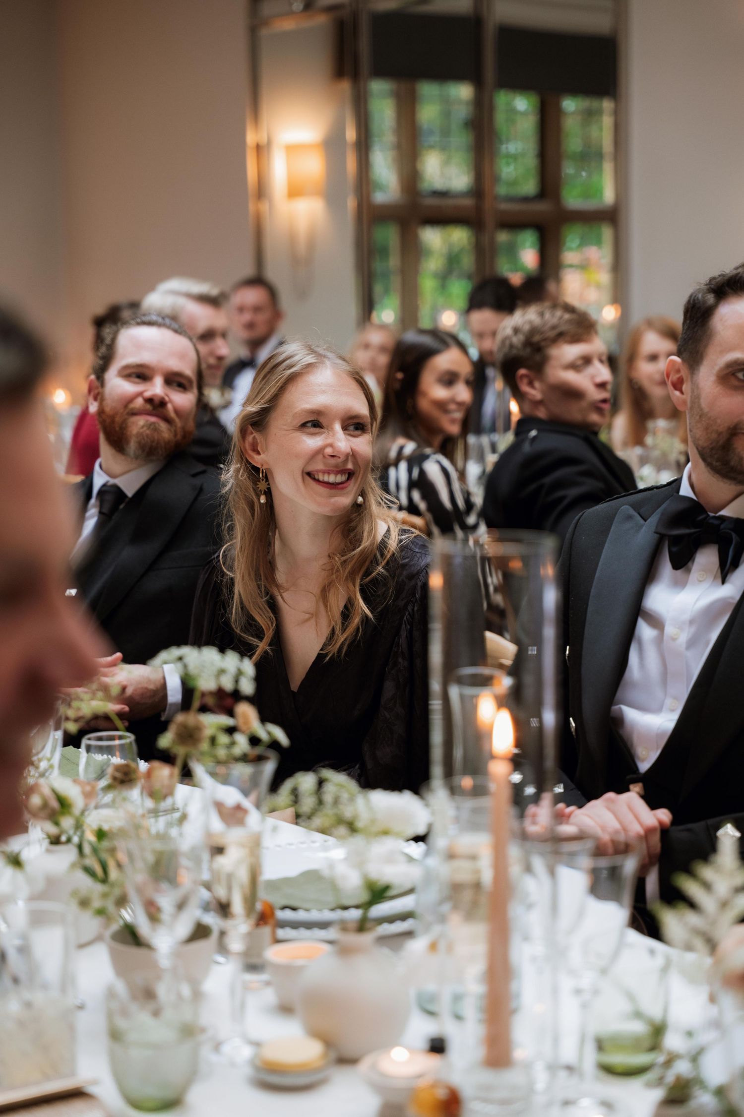 Guests enjoying an elegant dinner party with candlelight and table settings at a formal event.