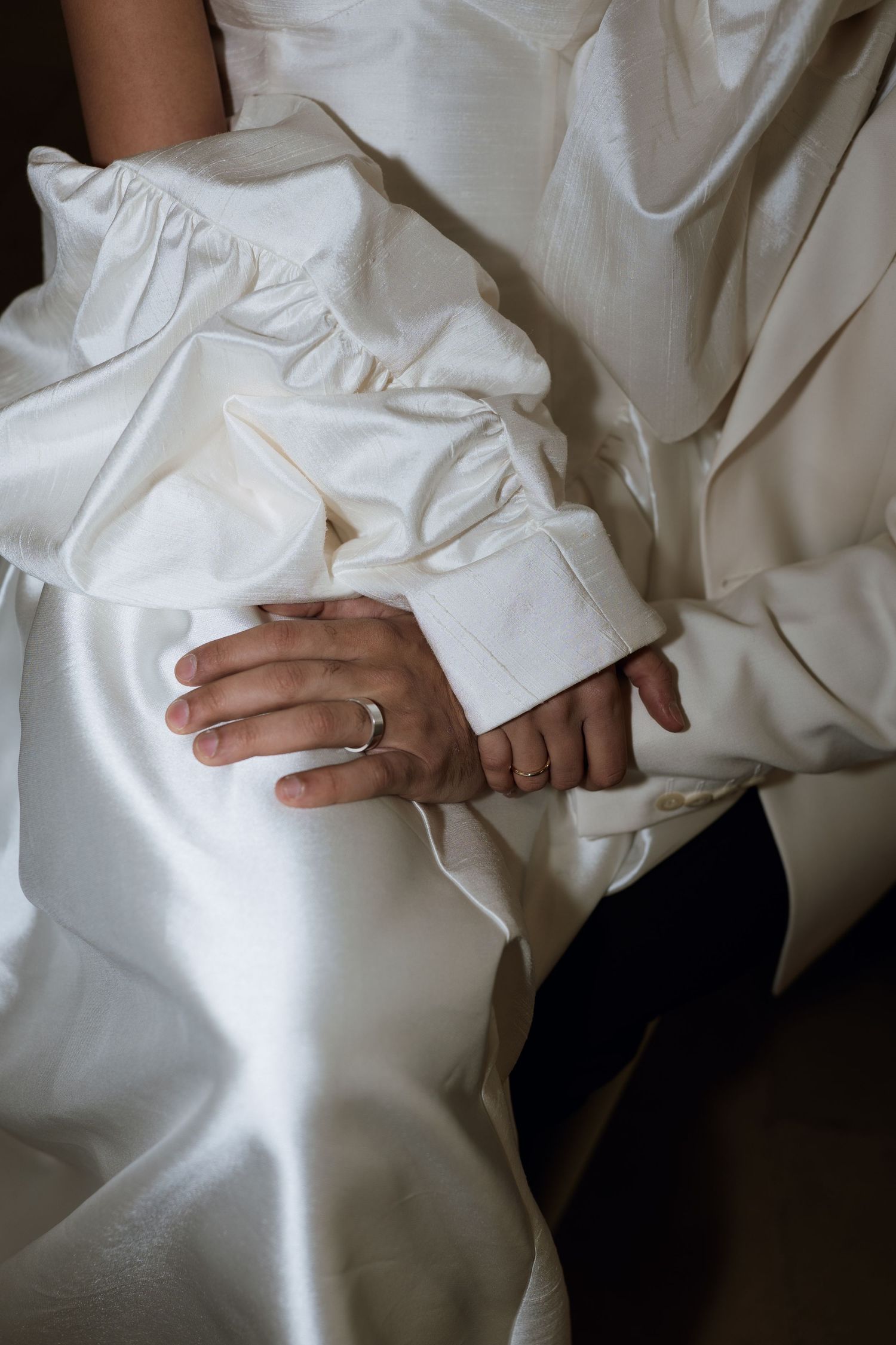 Close-up view of hands wearing a white dress shirt sleeve with a wedding ring detail.