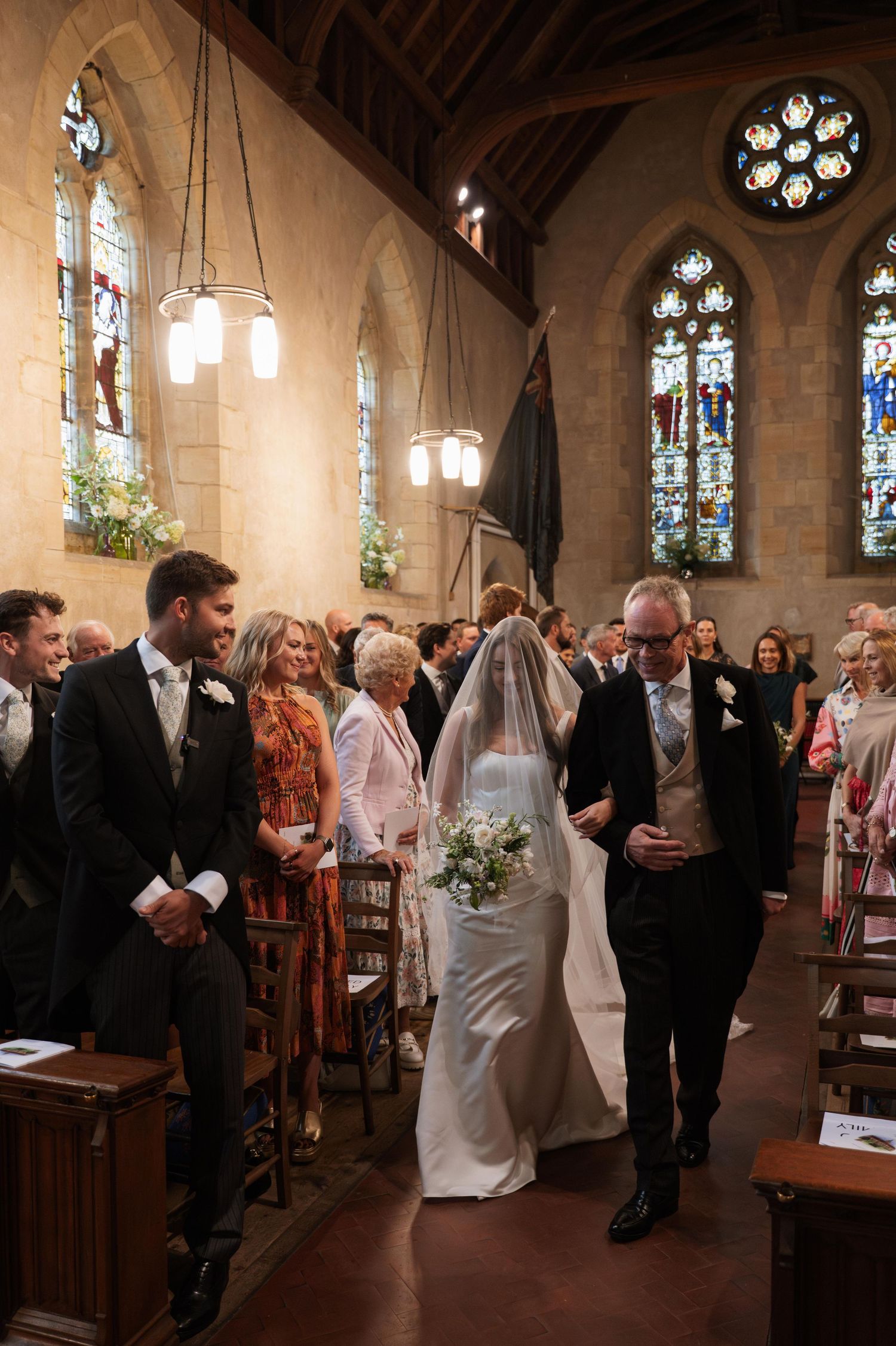 A wedding ceremony taking place in a beautiful Gothic church with stained glass windows and wooden pews.