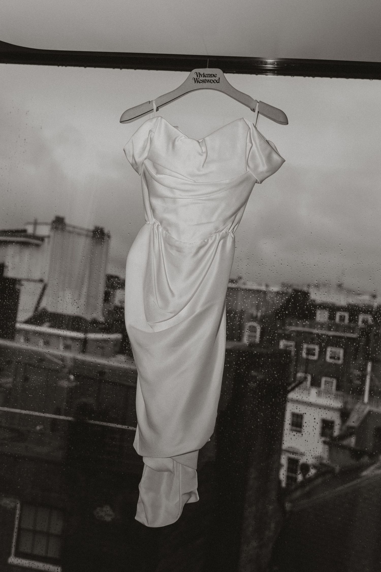 A series of black and white photographs showing a white dress or garment hanging against an urban rooftop backdrop.