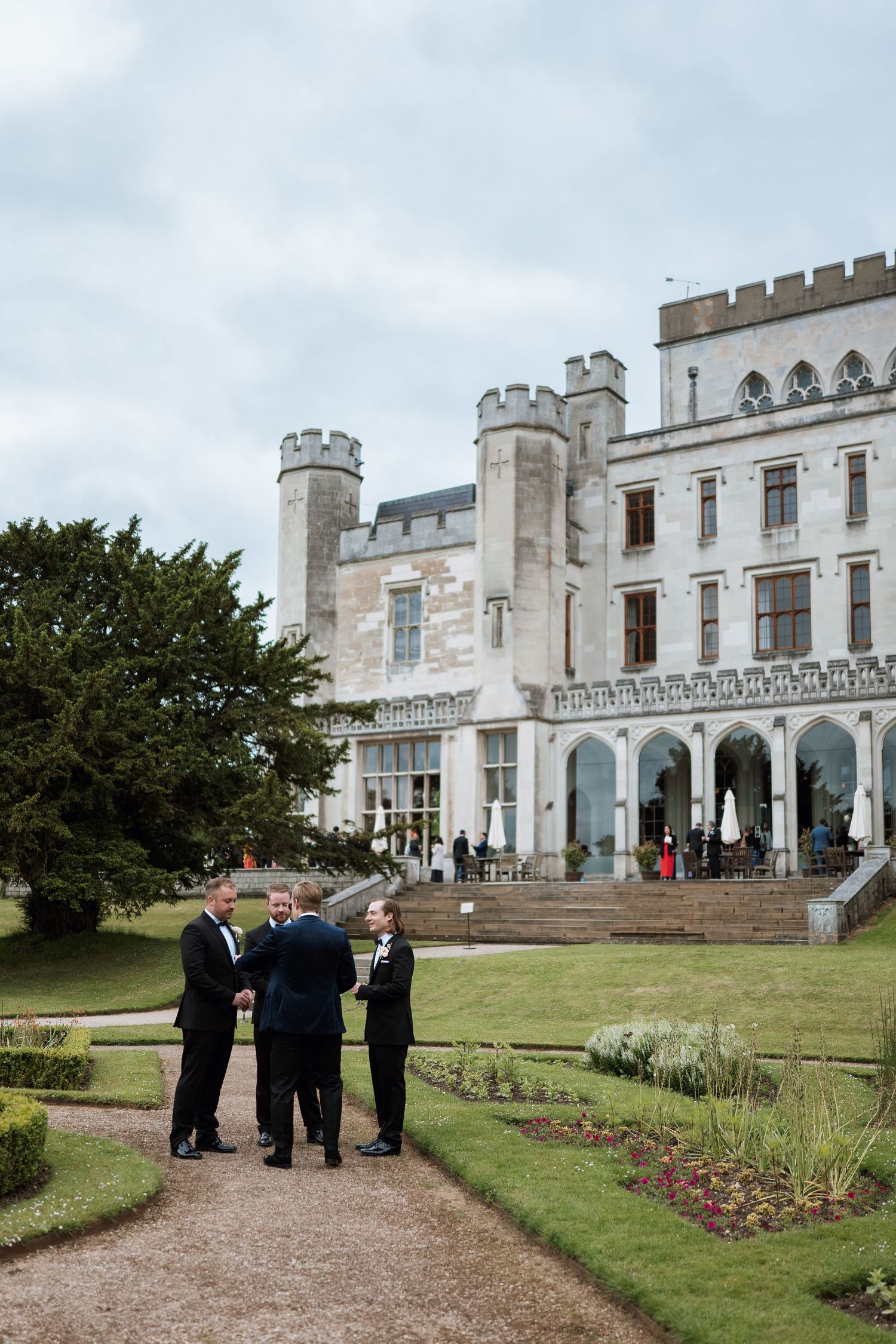 Image of wedding guests gathered outside a white castle-style building with crenellated walls and towers.