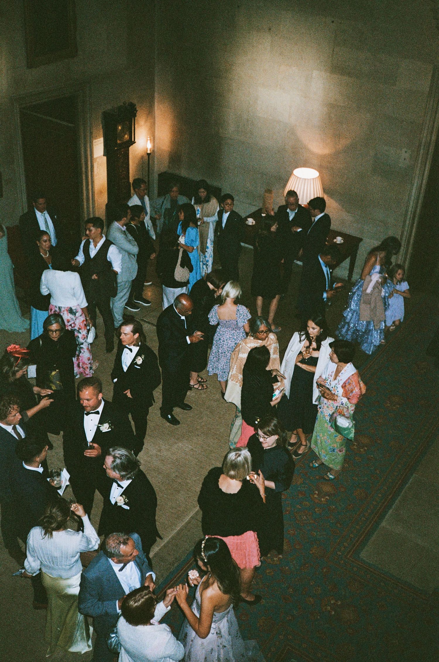 People dancing and socialising at ashridge house during a wedding event with dim lighting and elegant decor.