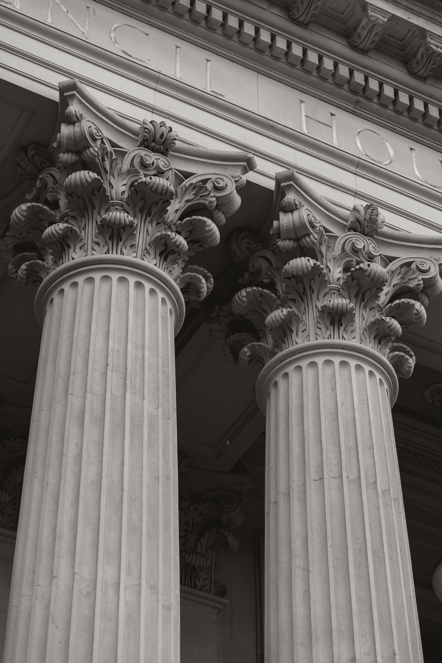 Close-up black and white architectural detail of ornate Corinthian columns with fluted shafts and decorative capitals.