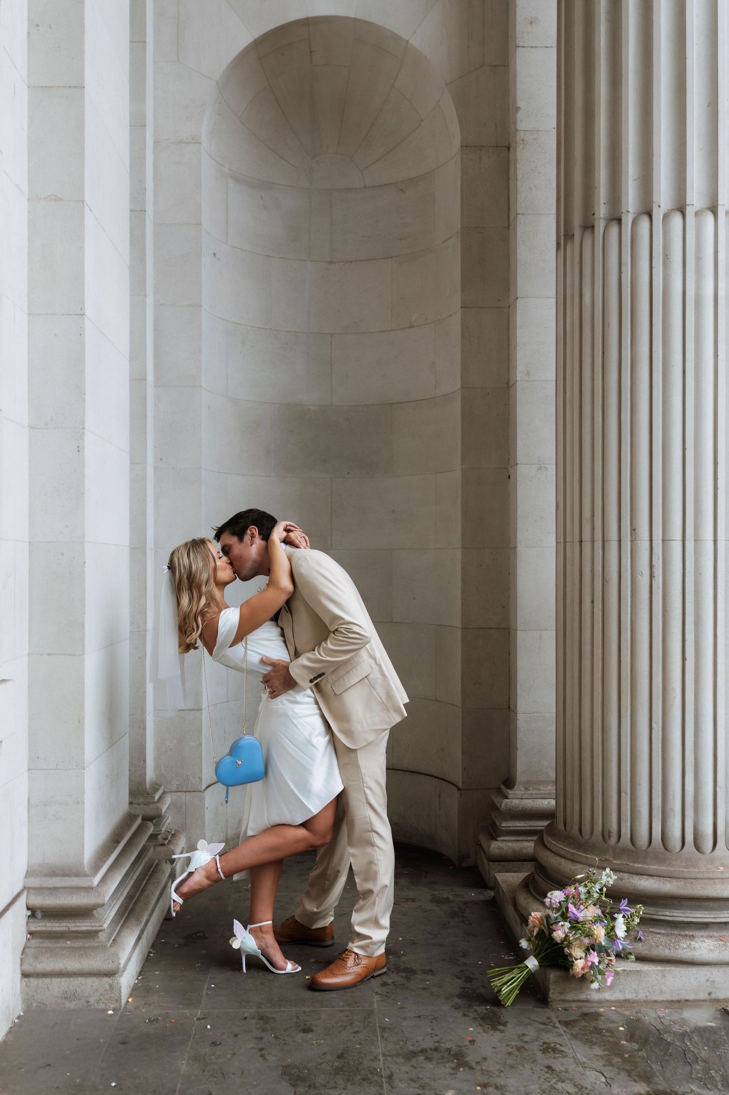Romantic couple shares intimate moments between classic white columns in an elegant architectural setting.