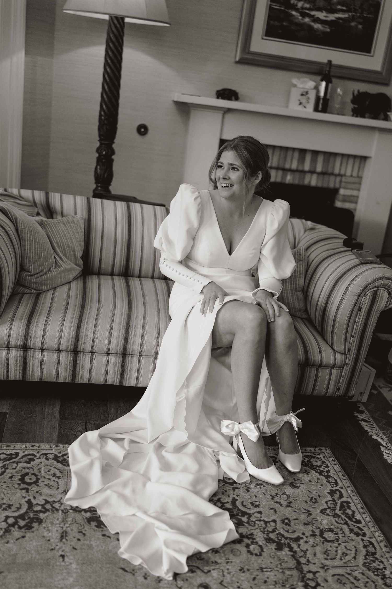 A black and white photo series showing a bride in a white wedding dress sitting on a striped couch in various poses.