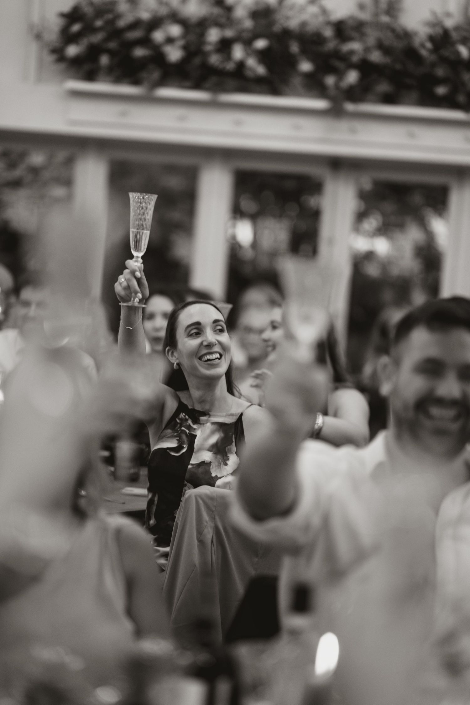 People enjoying a celebration with raised champagne glasses and laughter at an outdoor gathering.