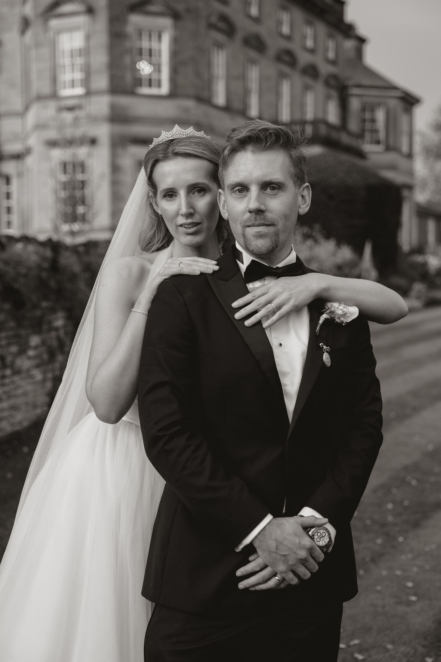 A series of black and white wedding photos showing a couple embracing outdoors near historic buildings.
