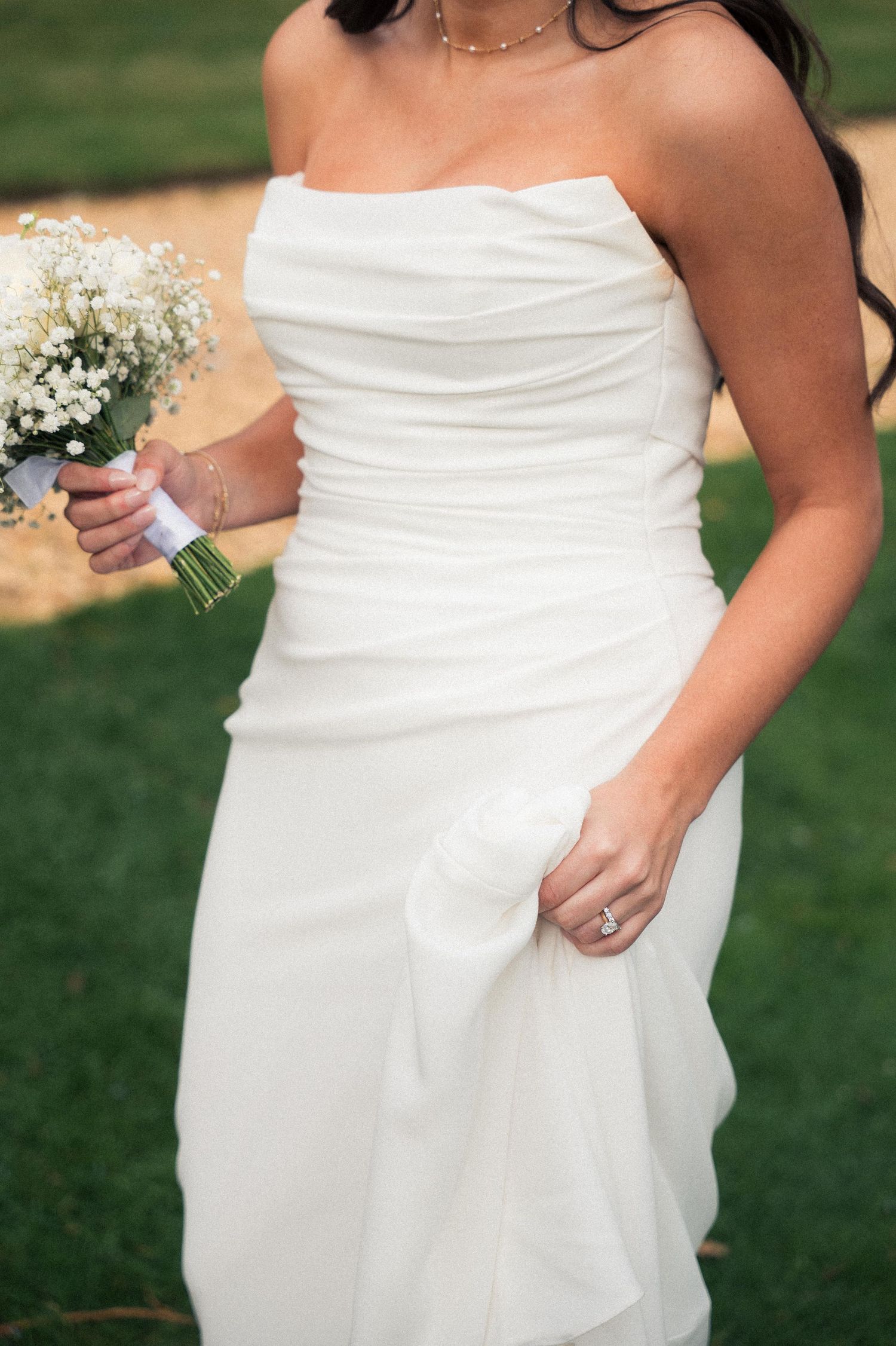Close-up details of a white wedding dress with elegant ruching and draping shown from different angles against a green lawn.